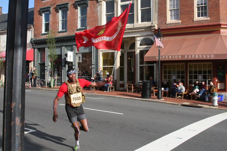 Joshua Howze, 22, of Washington, D.C., rounds the corner of William Street in downtown Fredericksburg carrying the Marine Corps flag during the Historic Half marathon May 15.