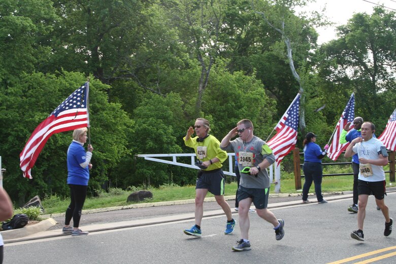 Runners salute the American flag as they pass along the Wear Blue Run to Remember Mile honoring Marines killed in action, a new feature of the Marine Corps Historic Half.