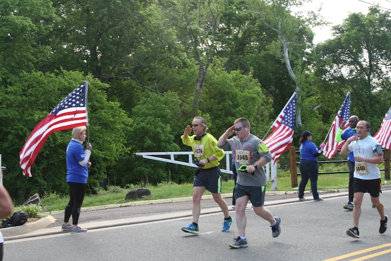 Runners salute the American flag as they pass along the Wear Blue Run to Remember Mile honoring Marines killed in action, a new feature of the Marine Corps Historic Half.