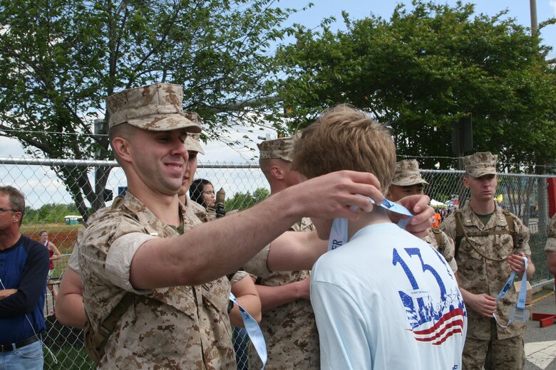 Lieutenants present medals to runners completing the ninth annual Marine Corps Historic Half.