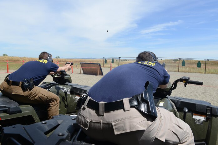 Sean Gatton (right), Air Force Office of Special Investigations special agent and David Shaver, AFOSI special agent, fire their pistols while mounted on ATV’s during a shooting competition May 18, 2016, at Beale Air Force Base, California. Multiple two-man teams from various military and civilian law enforcement agencies participated during the competition. (U.S. Air Force photo/ Senior Airman Bobby Cummings)