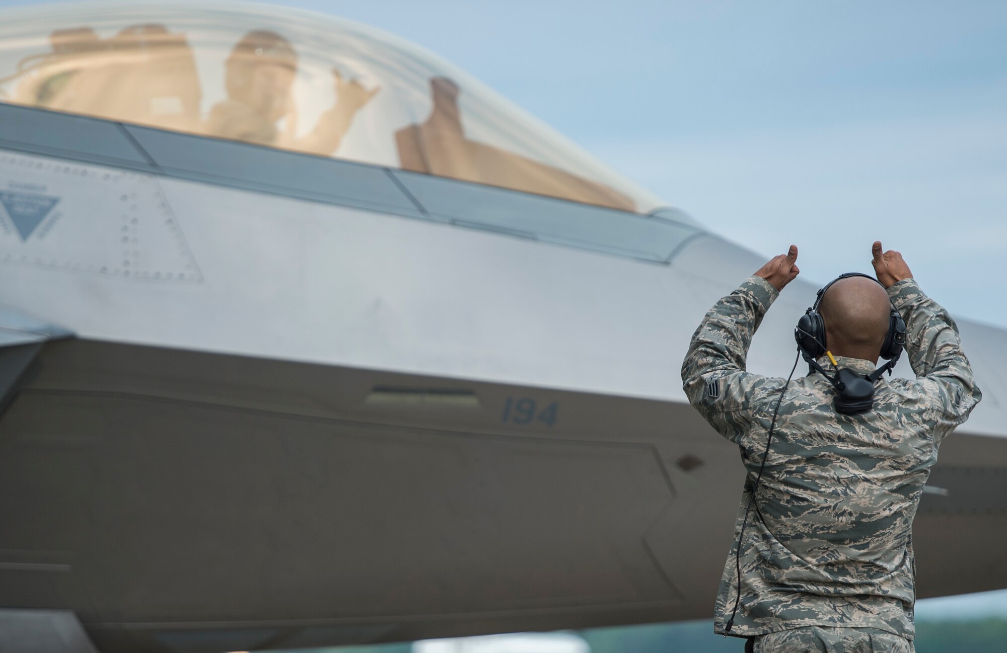 U.S. Air Force Senior Airman Ismael Debarros, an F-22 Raptor crew chief assigned to the 94th Aircraft Maintenance Unit, marshals out an F-22 Raptor at Langley Air Force Base, Va., May 19, 2016. The Raptors will be participating in a joint, tactical air combat employment exercise, which they have been preparing four months for.  (U.S. Air Force photo by Senior Airman Kayla Newman)
