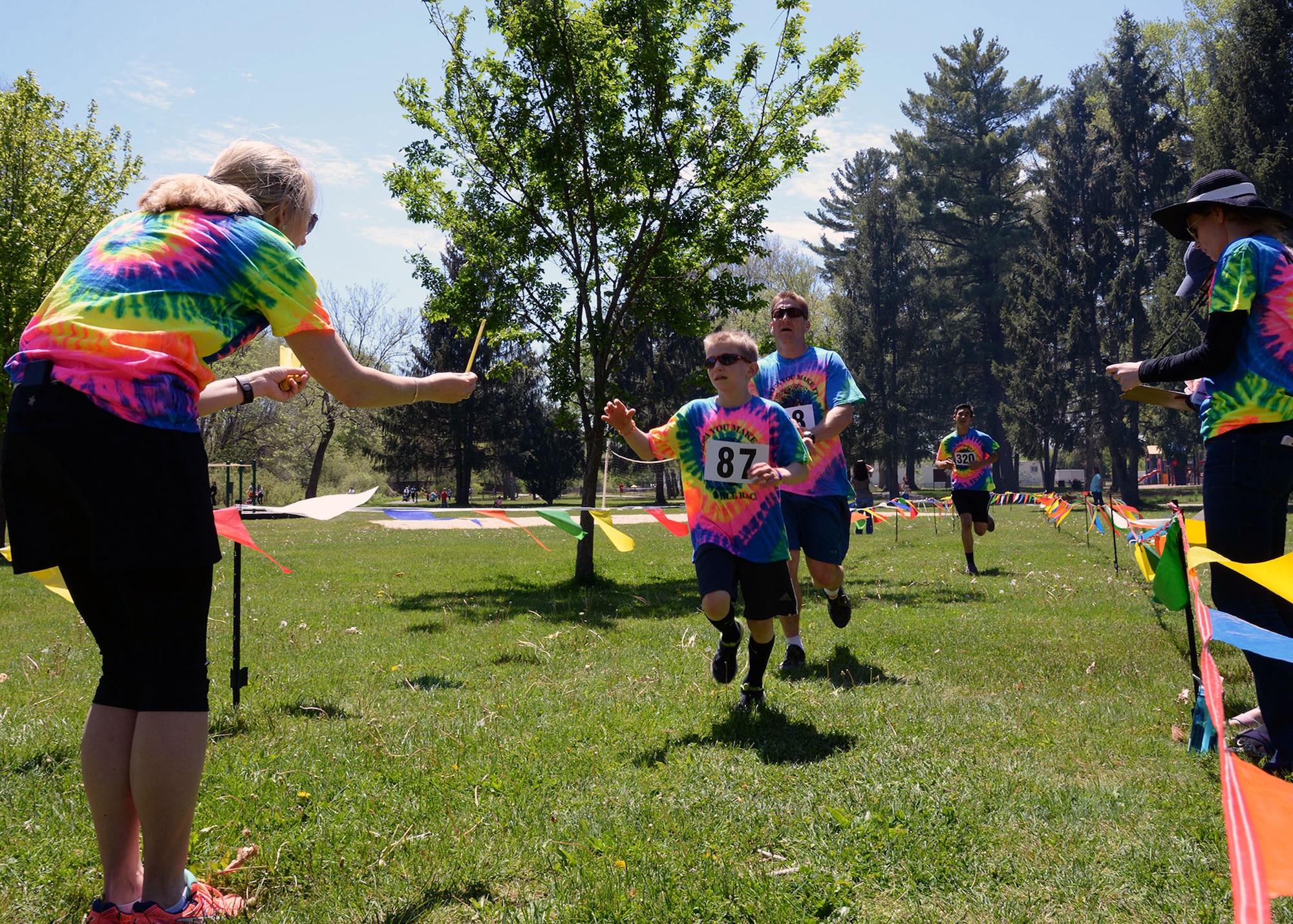 Stacey Clarkin, a wellness teacher at the Hanscom Middle School, hands fourth grader Travis Rabe a stick during the annual HOPA You Can Make It Three Mile Race on base May 18. This is the 31st running of the race, named after the Hopa Crabapple trees planted many years ago near the finish line of the three mile race. (U.S. Air Force photo by Linda LaBonte Britt)