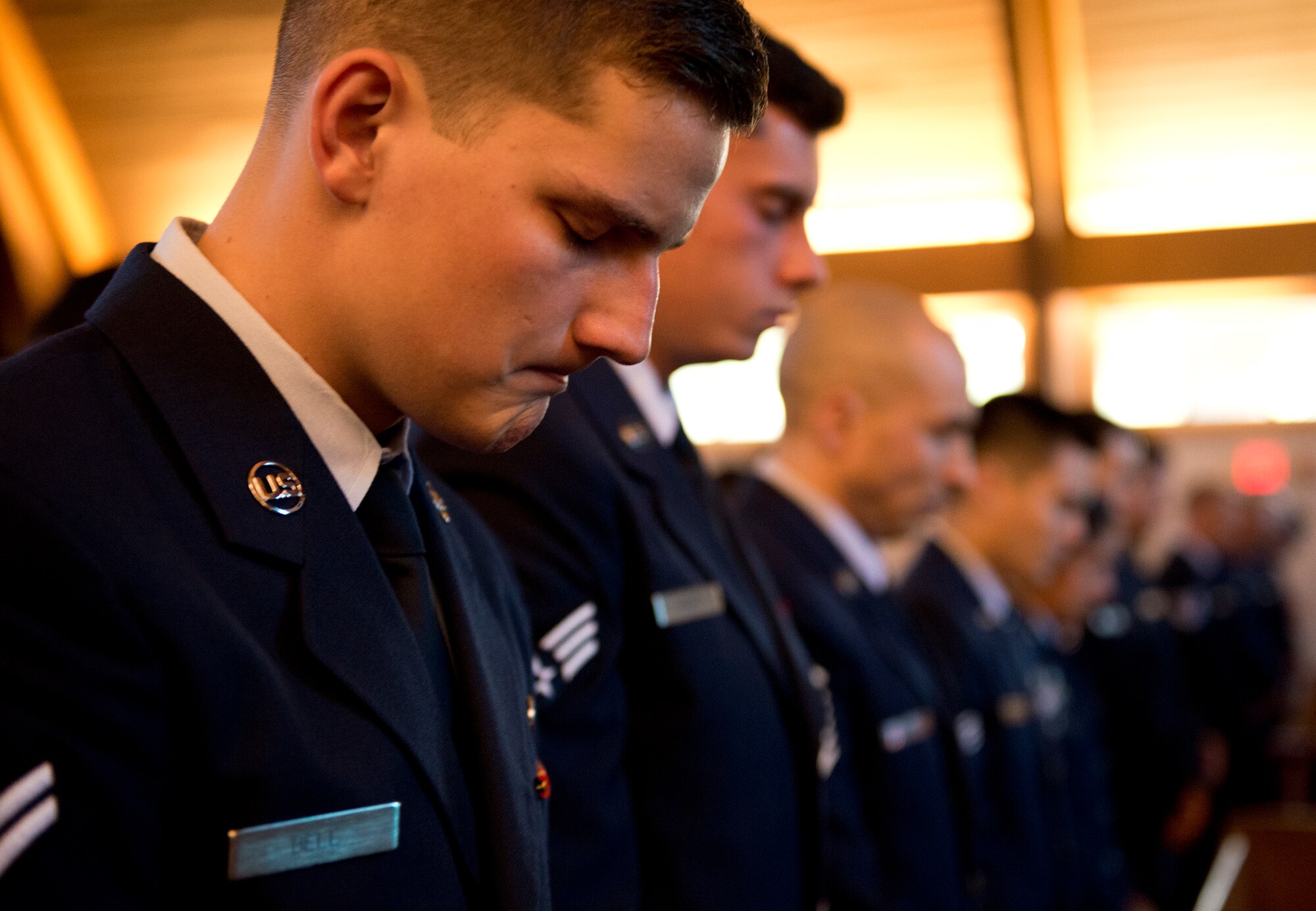 Airman 1st Class Clayton Bell, 96th Security Forces Squadron, and many fellow defenders bow their heads during a moment of silence during the candle light vigil May 19 at Eglin Air Force Base, Fla.  The ceremony was held to honor the fallen police, defenders and agents from the previous year during National Police Week.  Nine candles were lit in remembrance including one for Okaloosa County Sheriff’s Deputy Bill Myers and Special Agent Adrianna Vorderbruggen.  (U.S. Air Force photo/Samuel King Jr.)