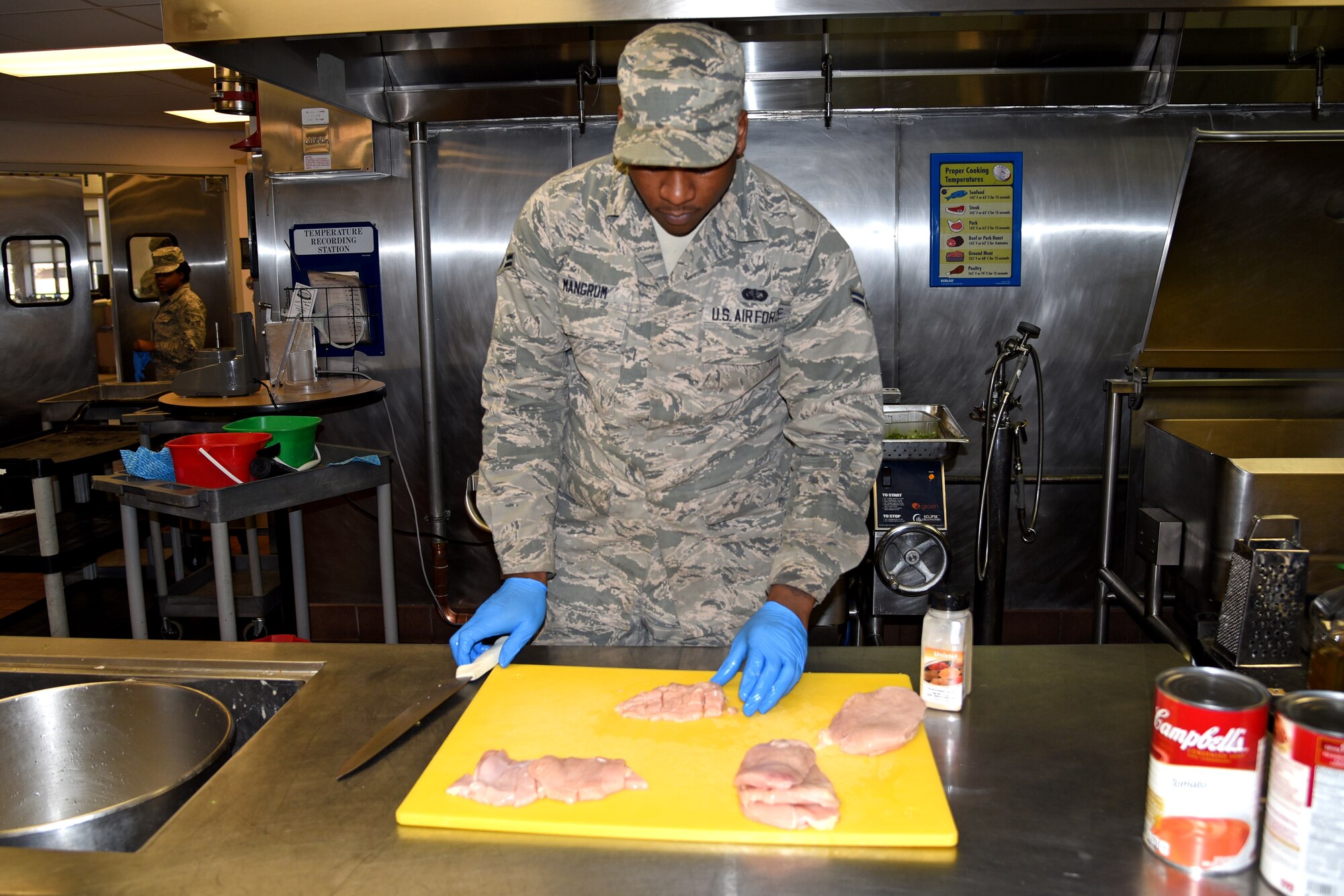 Airman 1st Class Juwan Mangrun slices several pieces of chicken cutlets in preparation to serve lunch to Airmen at Halvorsen Hall Dining facility at Joint Base McGuire-Dix-Lakehurst, N.J., April 16, 2016. Mangrun is a member of the 108th Sustainment Services Flight. (U.S. Air National Guard photo by Airman Tech. Sgt. Armando Vasquez/Released)