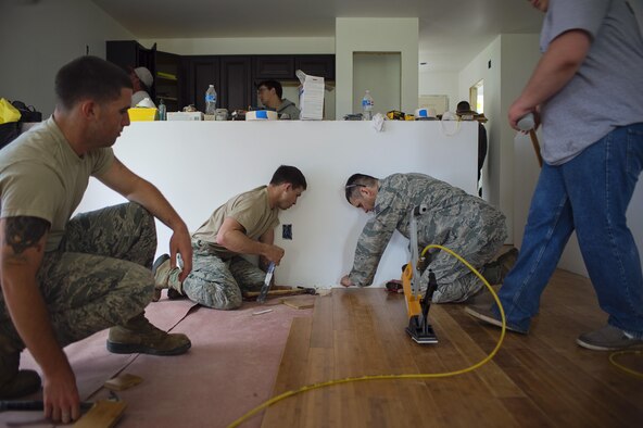 (From left to right) Senior Airman Joshua Harding, Staff Sgt. Samuel Kunker and Tech. Sgt. Michael Venture, all from the 512th Civil Engineer Squadron, place flooring in the new Habitat for Humanity house in downtown Dover, Del., May 22, 2016, alongside the nonprofit volunteers to provide housing forindividuals and families in need. The house build is able to satisfy certain training requirements needed for 512th CE Airmen while also providing a real-world benifit to families in the local community. (U.S. Air Force photo/Capt. Bernie Kale)