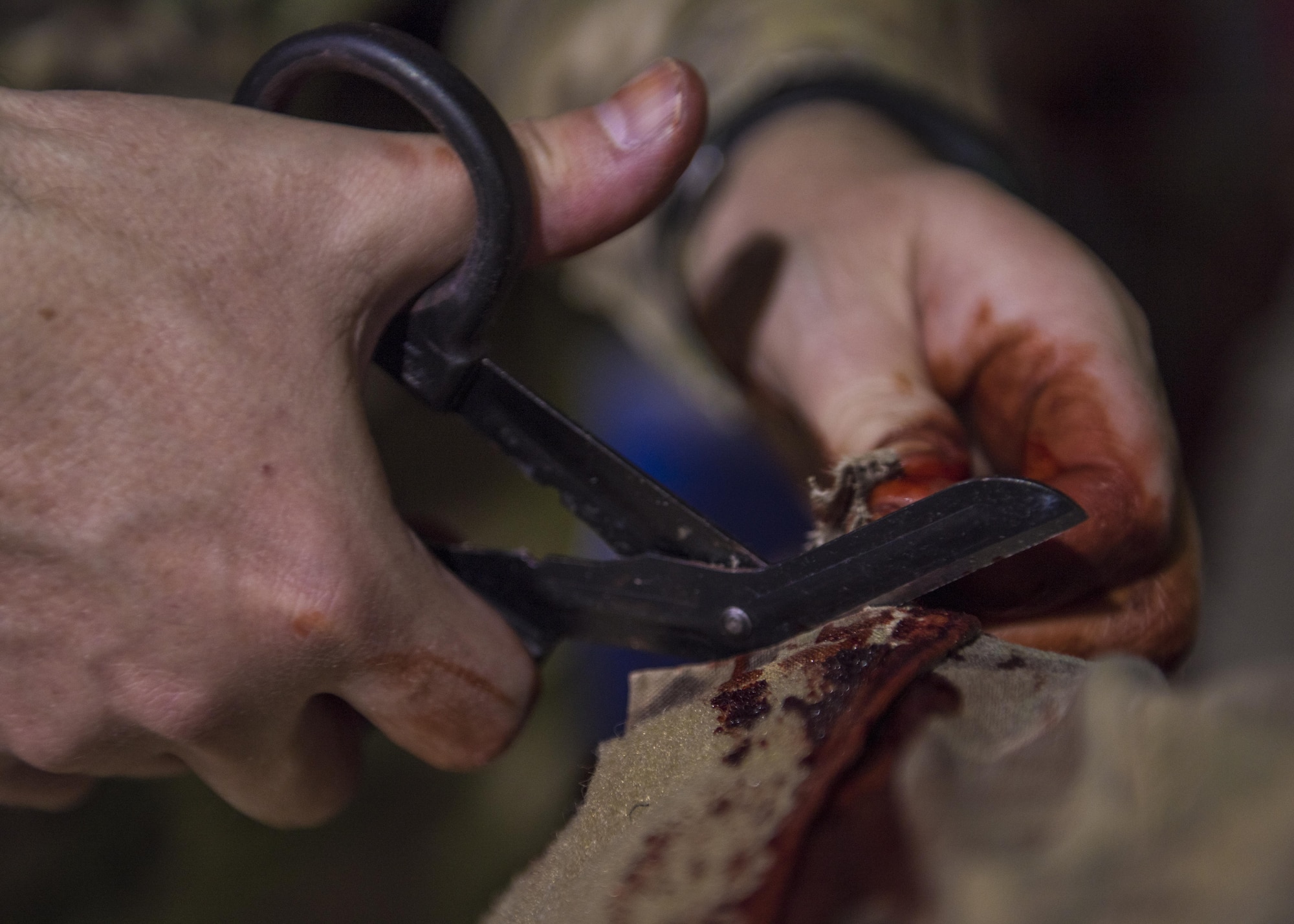 A Department of Defense civilian cuts open an Operationary Camouflage Pattern uniform during the application of moulage for a mass casualty exercise at Bagram Airfield, Afghanistan, May 21, 2016. The application of moulage to Airmen provides a sense of realism in exercises that medics and first responders may encounter in real-world accidents. (U.S. Air Force photo by Senior Airman Justyn M. Freeman)
