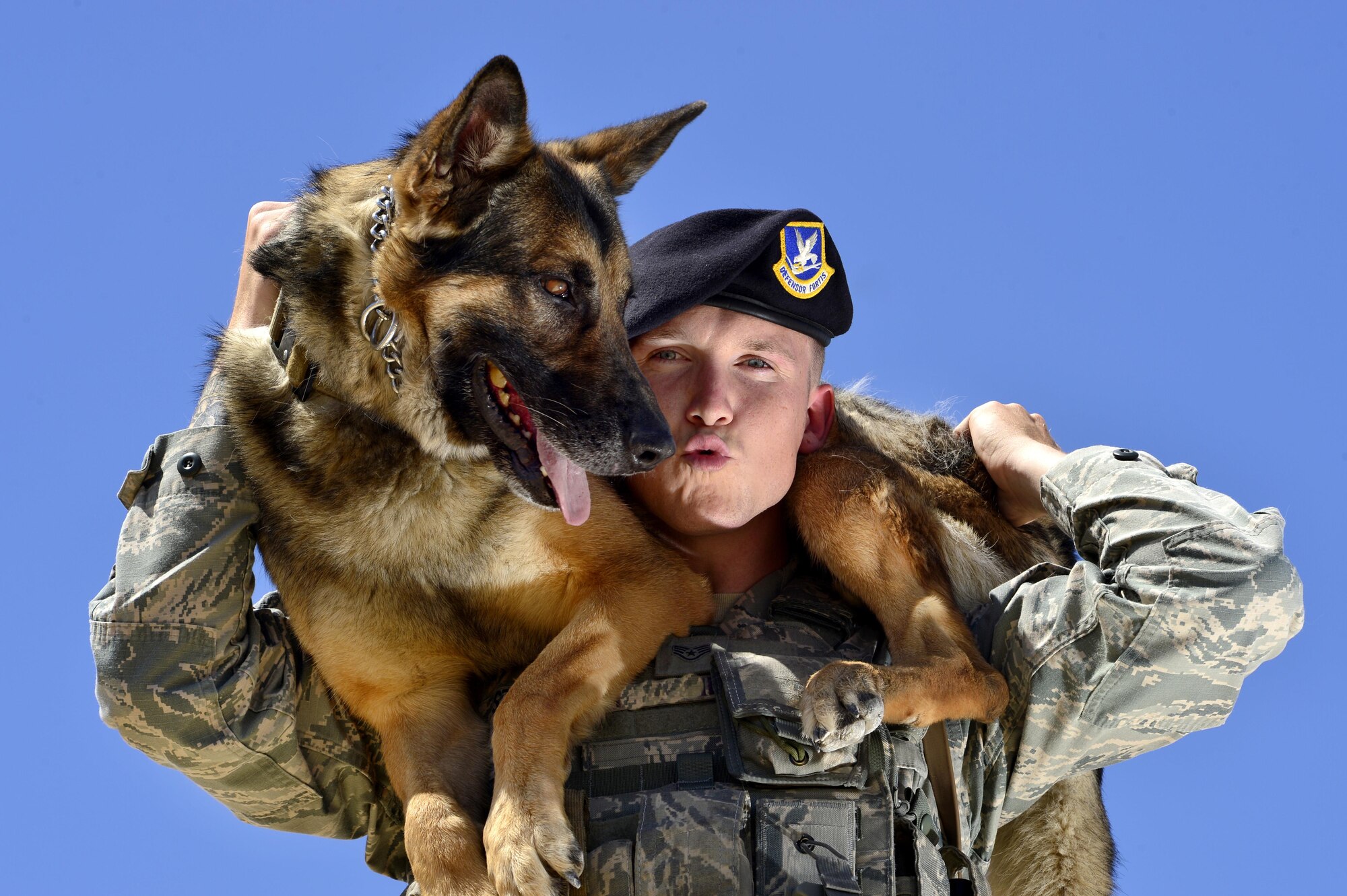 Staff Sgt. John, 799th Security Forces Squadron military working dog handler, poses for a photo with MWD Toby May 10, 2016, at Creech Air Force Base, Nevada. For National Police Week, security forces defenders came together for a MWD demonstration and life of a warrior fitness challenge, and a retreat ceremony to honor the sacrifices of civilian and military law enforcement personnel. (U.S. Air Force photo by Senior Airman Christian Clausen/Released)