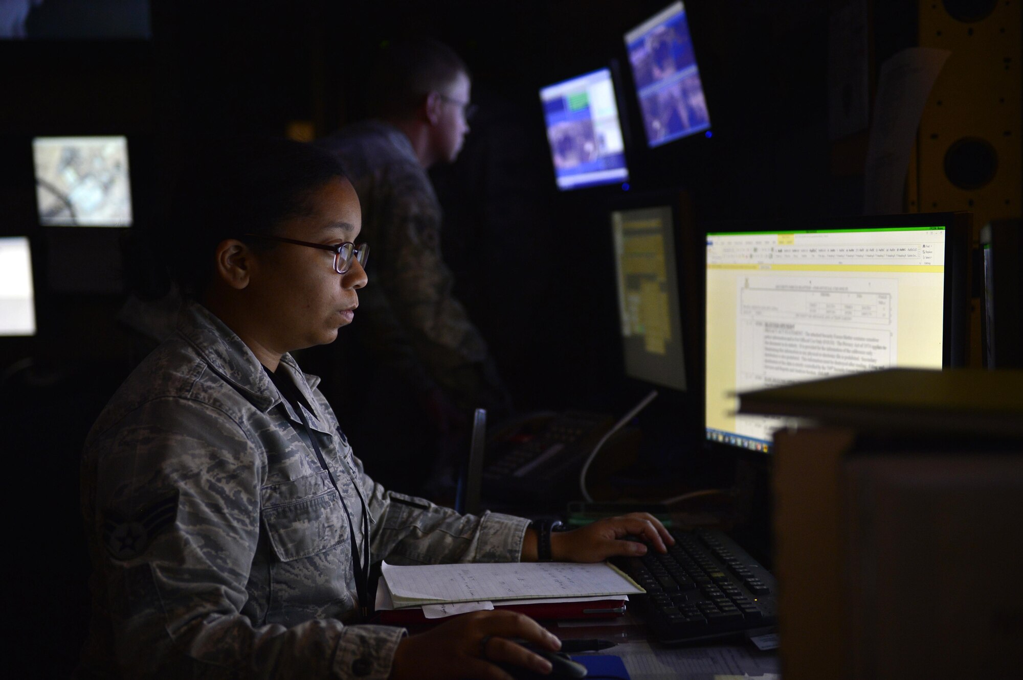 Senior Airman Stephanie, 799th Security Forces Squadron base defense operations center controller, front, processes requests while Airman 1st Class Bud, 799th SFS alarm monitor, checks perimeter cameras May 16, 2016, at Creech Air Force Base, Nevada. As part of National Police Week security forces defenders came together during a military working dog demonstration at a local high school, life of a warrior fitness challenge, and a retreat ceremony. (U.S. Air Force photo by Senior Airman Christian Clausen/Released)