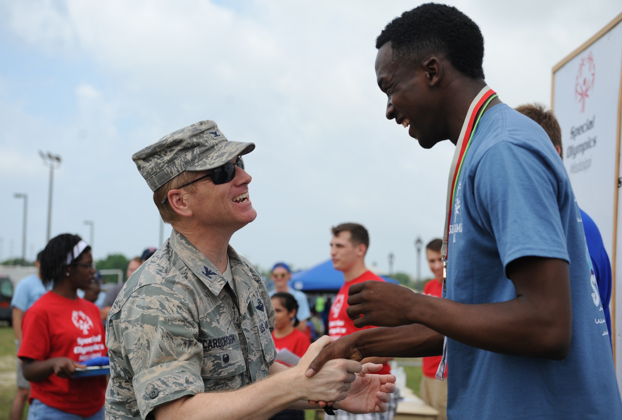 Col. Dennis Scarborough, 81st Training Wing vice commander, congratulates Desmond Brown, Special Olympics athlete, on earning a gold medal in the 50 meter race during the Special Olympics Mississippi Summer Games at the triangle track May 21, 2016, Keesler Air Force Base, Miss. More than 700 athletes and 3,000 volunteers worked together to hold competitions throughout the day. This is the 30th year Keesler has hosted the state Special Olympics.  (U.S. Air Force photo by Kemberly Groue)