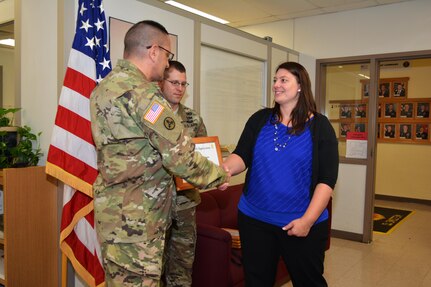 Col. Lawrence Leon, commander 3rd Ordnance Brigade 94th Training Division, thanks Liane Haun for her role in supporting the ammunition specialist reclassification course transition from Ft. Lee, Va., to Fort McCoy, Wis. Leon also presented Haun with his commanders coin and a certificate of appreciation during an impromptu ceremony at Fort McCoy, May 13, 2016. As a real estate planner, Haun’s efforts included acquiring buildings for the classes. The 94th Training Division will begin the phased move of Ammunition Stock Control and Accounting Specialist, Ammunition Specialist, courses to Fort McCoy for the start of FY17.