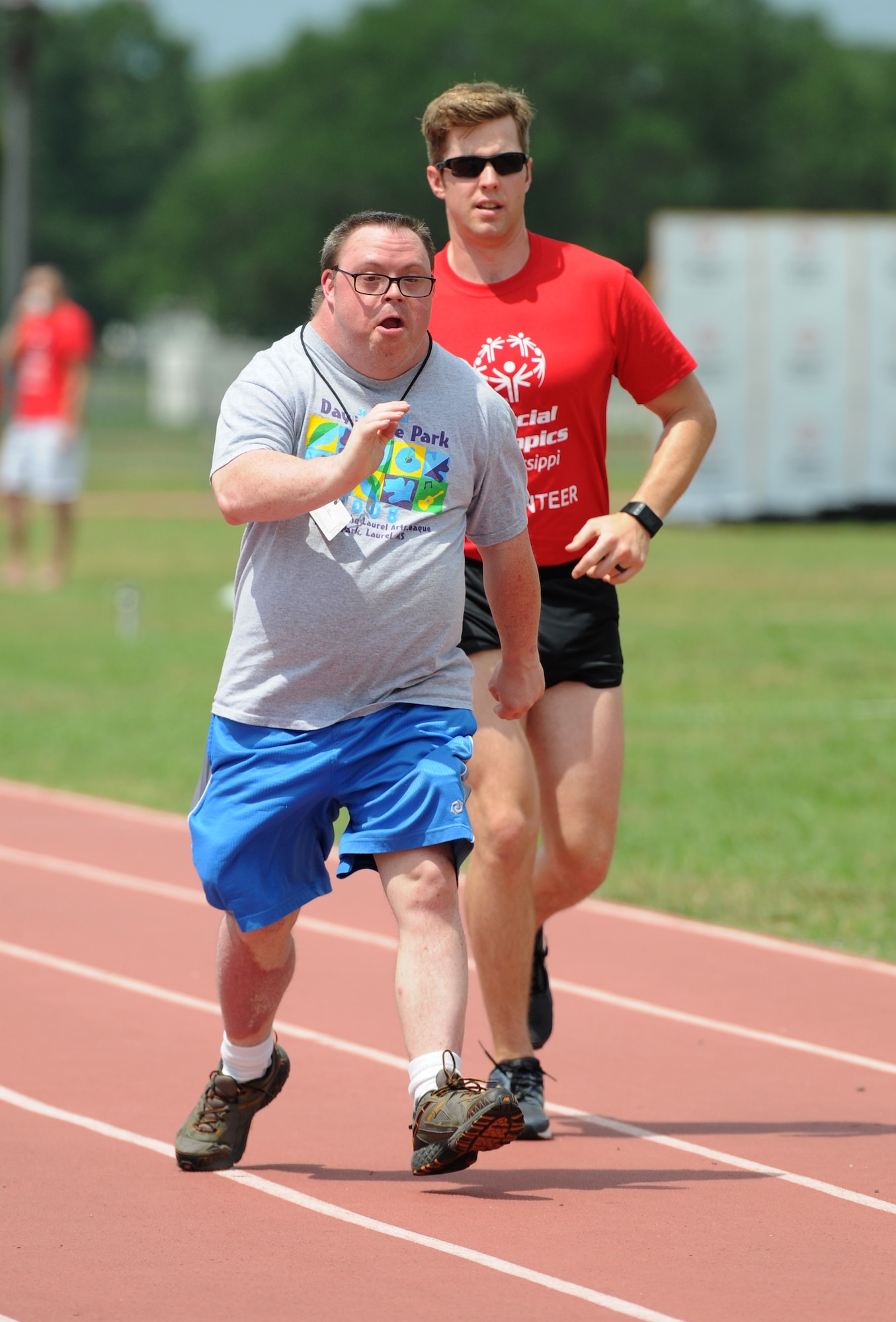 John Toche, Special Olympics athlete, participates in the 100 meter walk with the assistance of Airman 1st Class Joshua Hinson, 335th Training Squadron student, during the Special Olympics Mississippi Summer Games at the triangle track May 21, 2016, Keesler Air Force Base, Miss. More than 700 athletes and 3,000 volunteers worked together to hold competitions throughout the day. This is the 30th year Keesler has hosted the state Special Olympics.  (U.S. Air Force photo by Kemberly Groue)