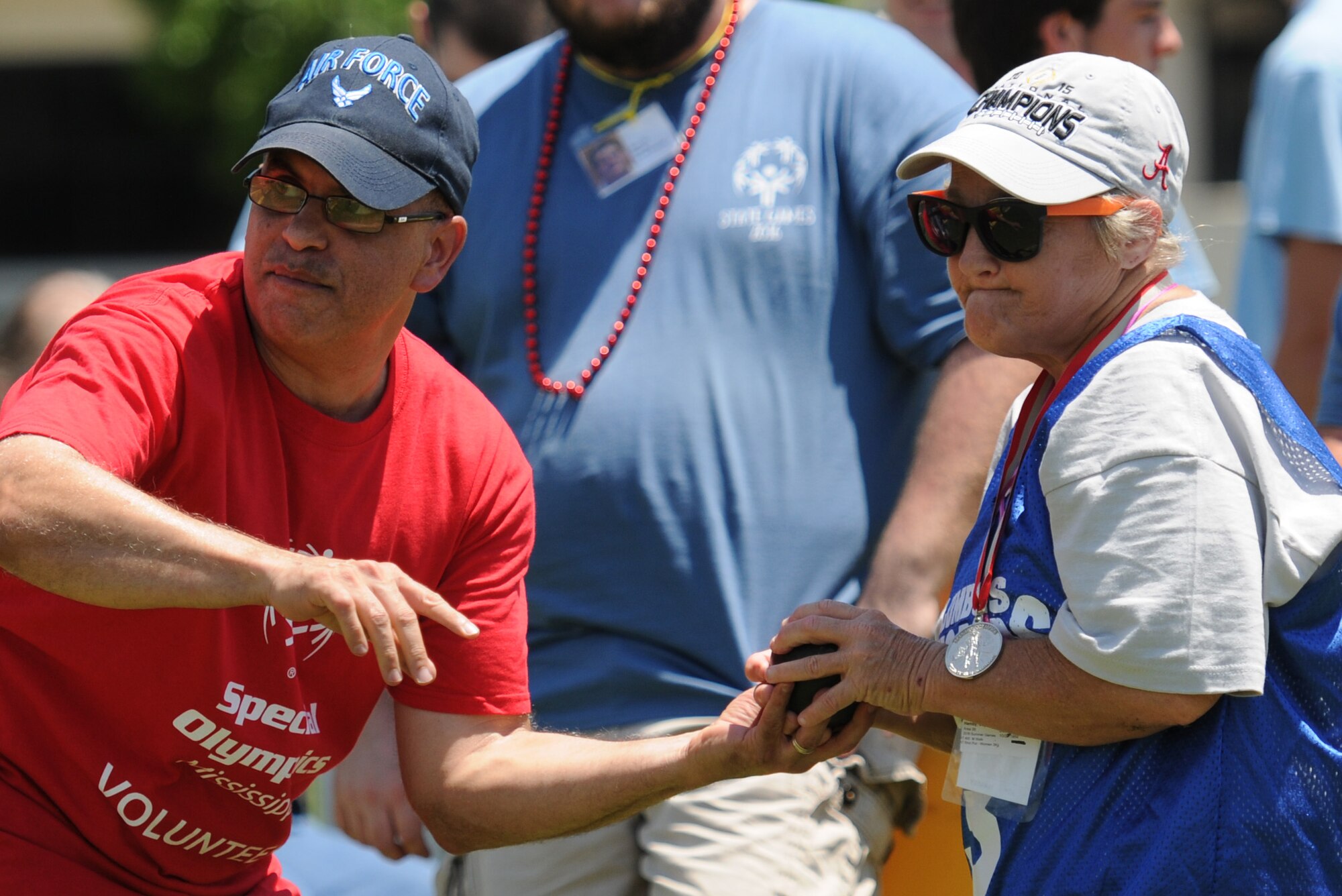 Jose Fuertes, 81st Communications Squadron information technology project manager, passes the shot put to Joy Hamby, Special Olympics athlete, during the Special Olympics Mississippi Summer Games at the Biloxi Natatorium May 21, 2016, Keesler Air Force Base, Miss. More than 700 athletes and 3,000 volunteers worked together to hold competitions throughout the day. This is the 30th year Keesler has hosted the state Special Olympics.  (U.S. Air Force photo by Kemberly Groue)