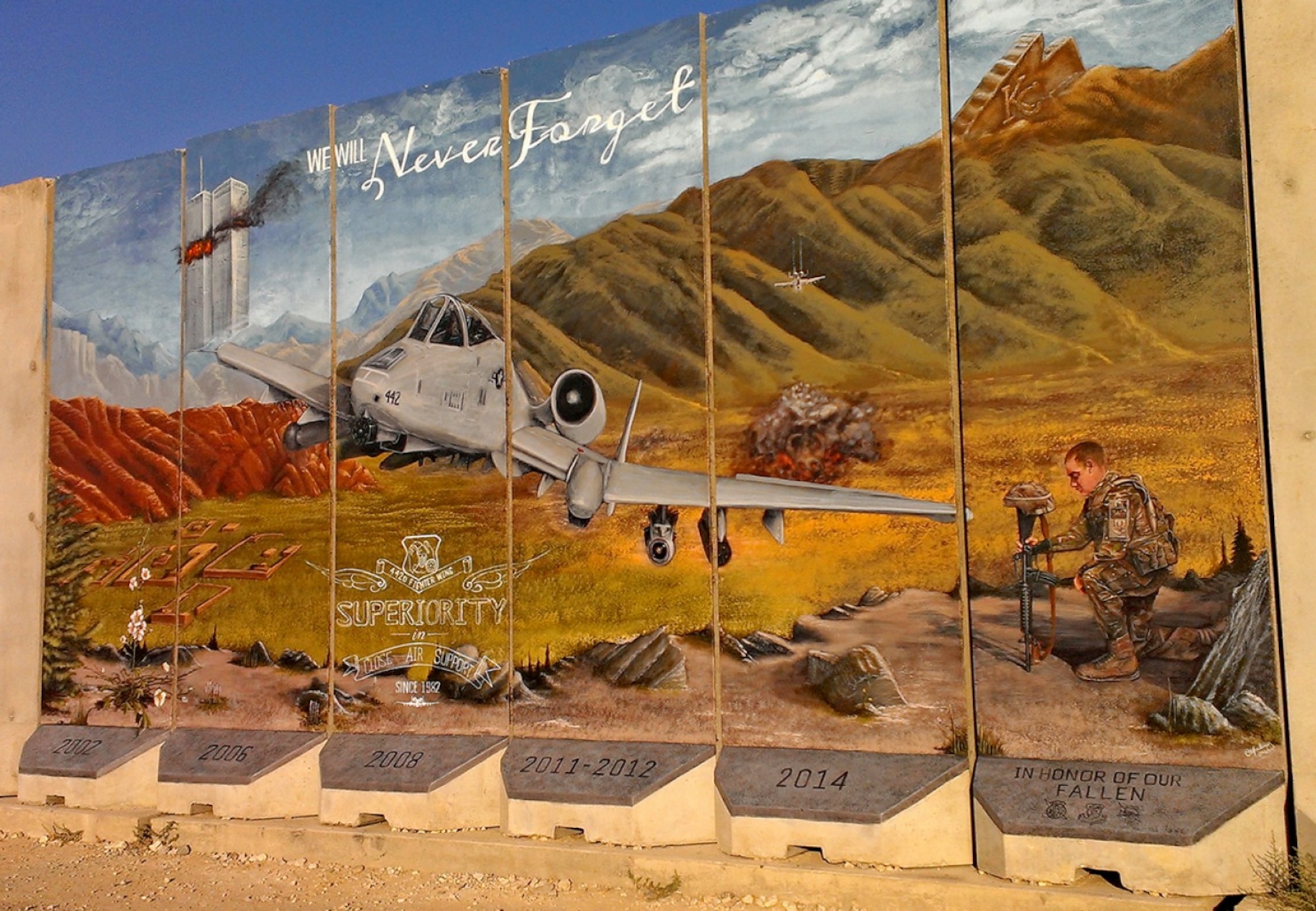 A mural by Staff Sgt. Omar, 432nd Wing sensor operator in training, depicts an A-10 Thunderbolt providing close air support in 2014, at a deployed location. Omar was previously assigned to the 442nd Fighter Wing at Whiteman Air Force Base, Missouri. On the left, the twin towers burn next to the words, “we will never forget,” to symbolize the events of September 11, 2001. On the right, Omar depicted one of his wingmen, an Airman holding a battle cross to commemorate fallen soldiers. (Courtesy Photo)