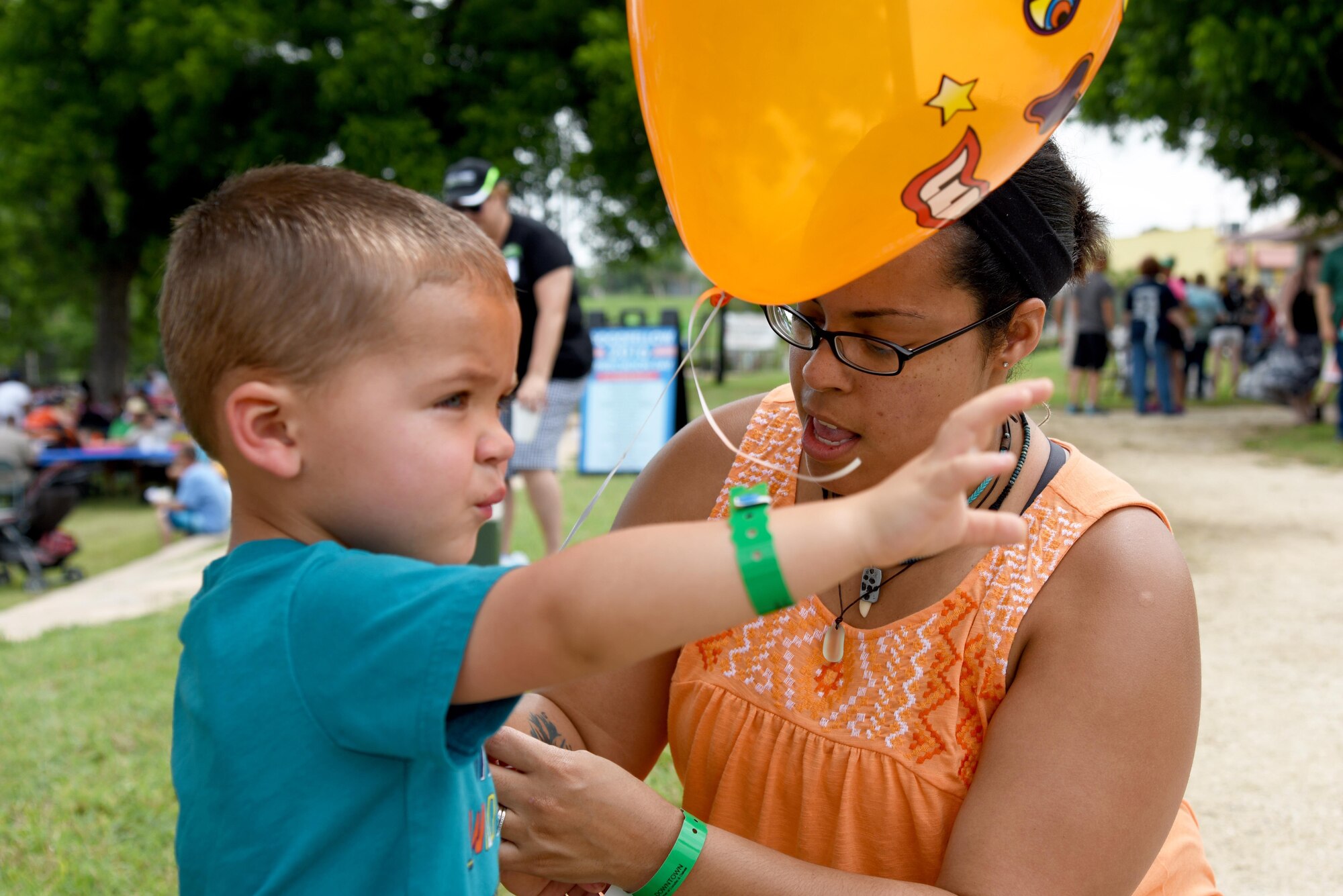 Stephanie Berg, Goodfellow Appreciation Day participant, ties a balloon to Jackson Berg’s arm at the RiverStage in San Angelo, Texas, May 21, 2016. The event had bounce houses, temporary tattoos and more to entertain children during the San Angelo Chamber of Commerce hosted Armed Forces Day celebration. (U.S. Air Force photo by Senior Airman Joshua Edwards/Released)