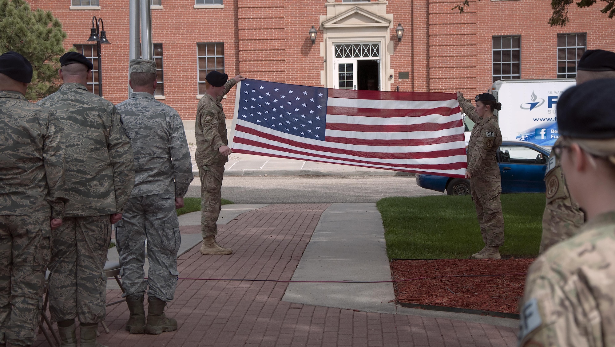 Senior Airman Joshua Hudson, 790th Missile Security Forces Squadron Tactical Response Force, and Senior Airman Kristin Pressler, 790th MSFS Convoy Response Force, prepare to fold an American Flag during a final guard mount and retreat ceremony on F.E. Warren Air Force Base, Wyo., May 20, 2016. The flag was ceremoniously folded and retired in honor of the security forces men and women who lost their lives in the past year. (U.S. Air Force photo by Senior Airman Brandon Valle)