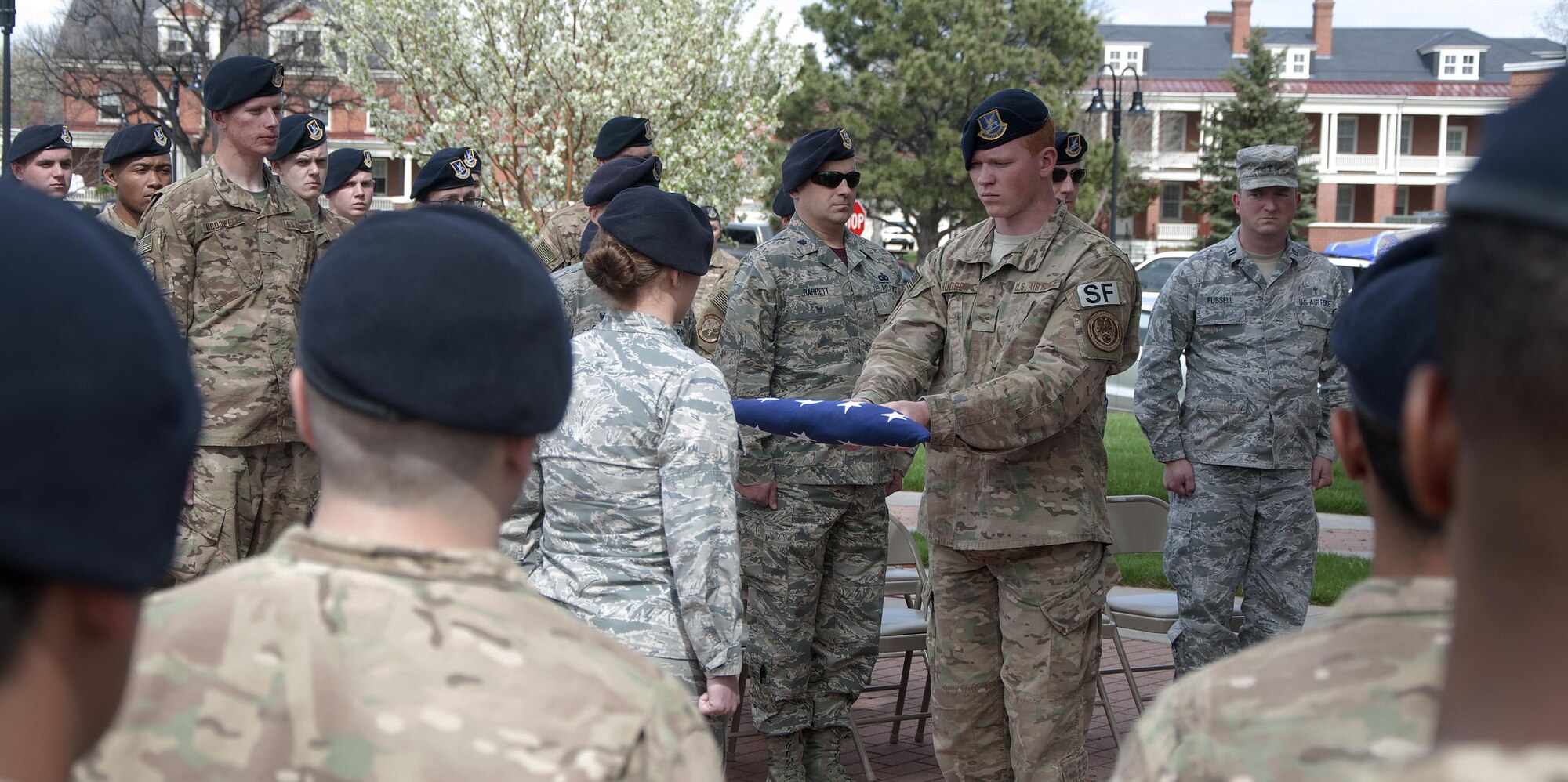 Senior Airman Joshua Hudson, 790th Missile Security Forces Squadron Tactical Response Force, presents a folded flag to 1st Lt. Katie Thalhamer, 90th Missile Security Forces Squadron, during a final guard mount and retreat ceremony on F.E. Warren Air Force Base, Wyo., May 16, 2016. The flag was retired to honor the men and women who have lost their lives in the line of duty as police in either civilian or military life. (U.S. Air Force photo by Senior Airman Brandon Valle)