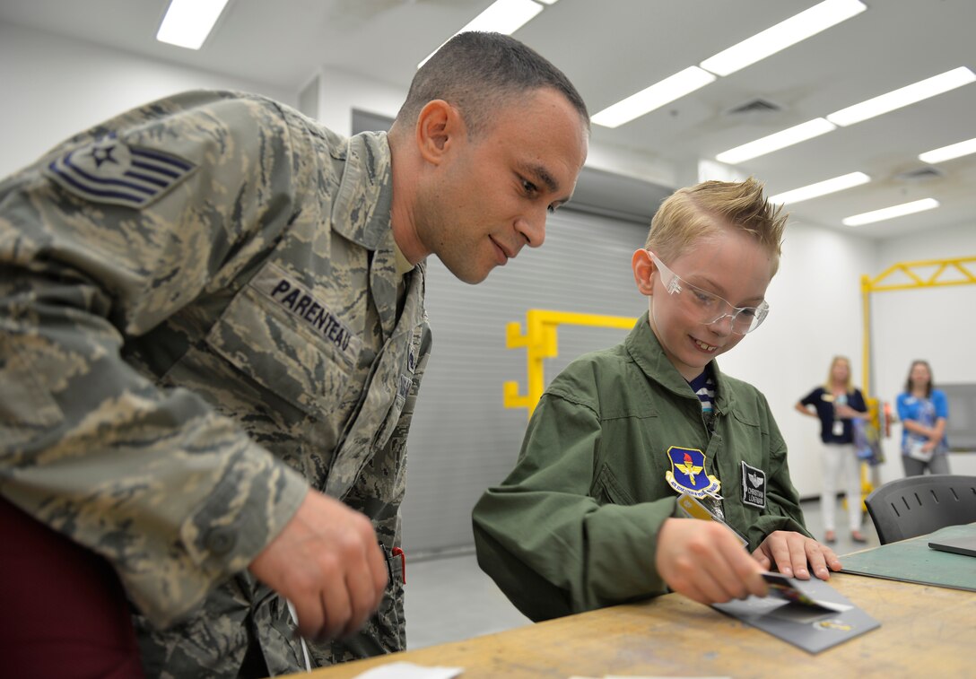 Tech. Sgt. Joseph Parenteau, 33rd Maintenance Squadron non-commissioned officer in charge of low observables, teaches Pilot for a Day, Christian Loafman, how to place lettering on aircraft metals at Eglin Air Force Base, Fla., May 18, 2016. Christian toured the low observable and non-destructive inspection shops where he learned how these Airmen check the aircraft to maintain its ability to fly safely. (U.S. Air Force photo/Senior Airman Andrea Posey)