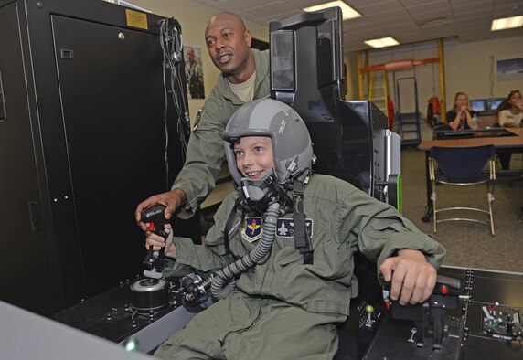 Tech. Sgt. Omar Robinson, 96th Medical Group aerospace and operational physiology technician, teaches Pilot for a Day, Christian Loafman, how to control flight simulator at Eglin Air Force Base, Fla., May 18, 2016. During the visit, Christian was treated like a real F-35A Lightning II pilot and given a flight equipment locker, flight suit and mission brief before he flew a mission using the flight simulator. (U.S. Air Force photo/Senior Airman Andrea Posey)