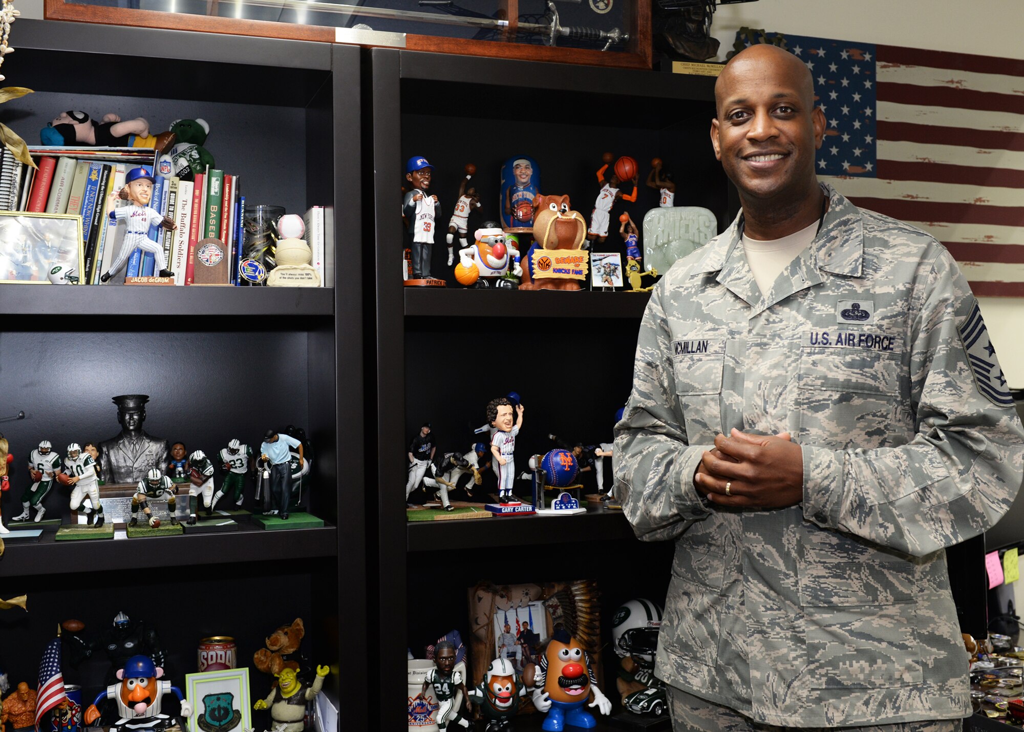 Chief Master Sgt. Michael McMillan, 36th Wing command chief, poses for a photo in front of his sports memorabilia collection Feb. 20, 2016, at Andersen Air Force Base, Guam. As command chief, McMillan’s responsibilities are to support the health and welfare of the Airmen of the 36th Wing and to ensure they have everything they need to complete the mission. (U.S. Air Force photo by Senior Airman Cierra Presentado)