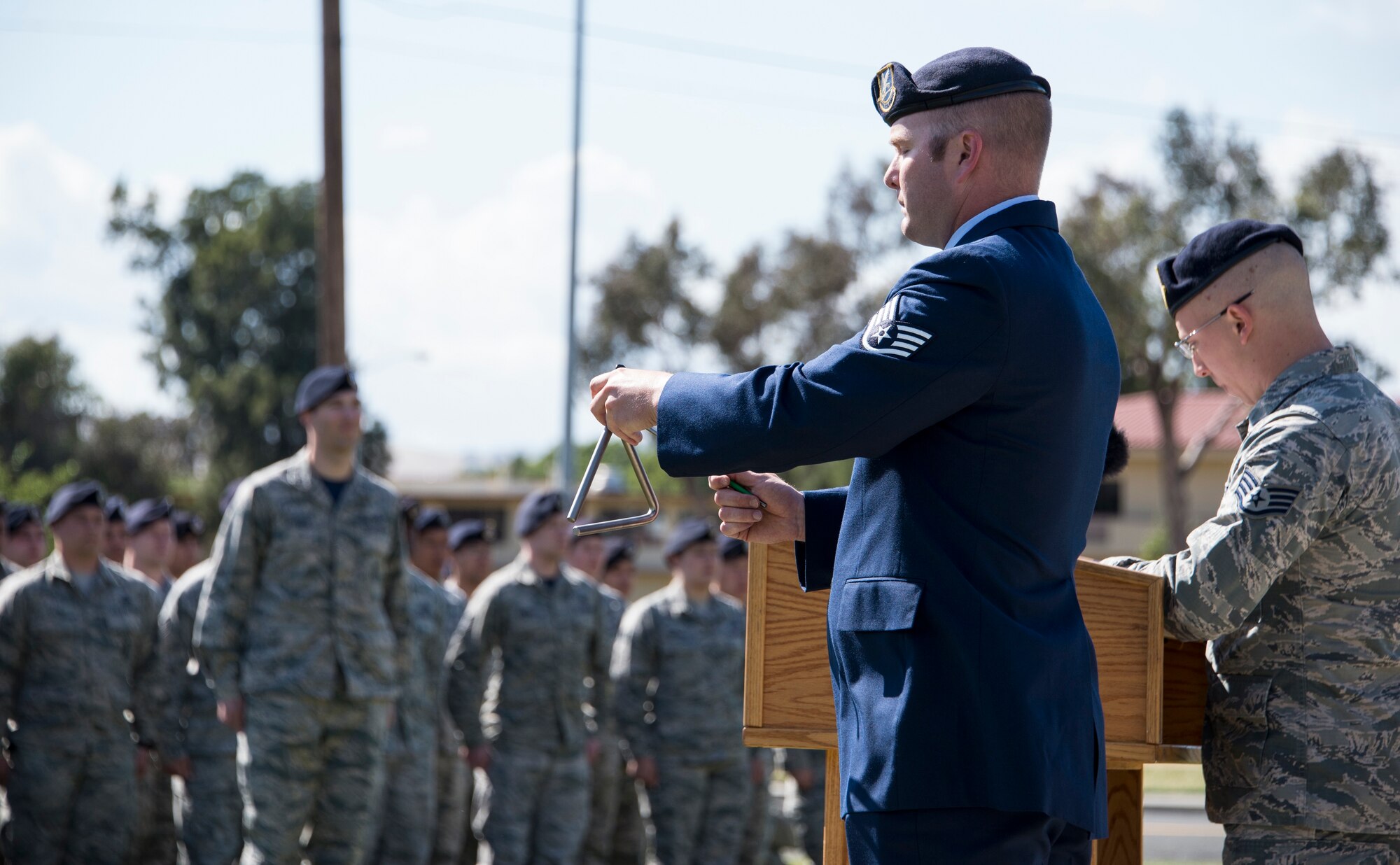 Staff Sgt. Michael Castaneda, 60th Security Forces Squadron, rings a triangle each time the name of a fallen service member is read aloud during a retreat ceremony at Travis Air Force Base, Calif., May 20, 2016. The retreat ceremony concluded a week of activities hosted by base security forces personnel as part of National Police Week. (U.S. Air Force photo by Staff Sgt. Charles Rivezzo)