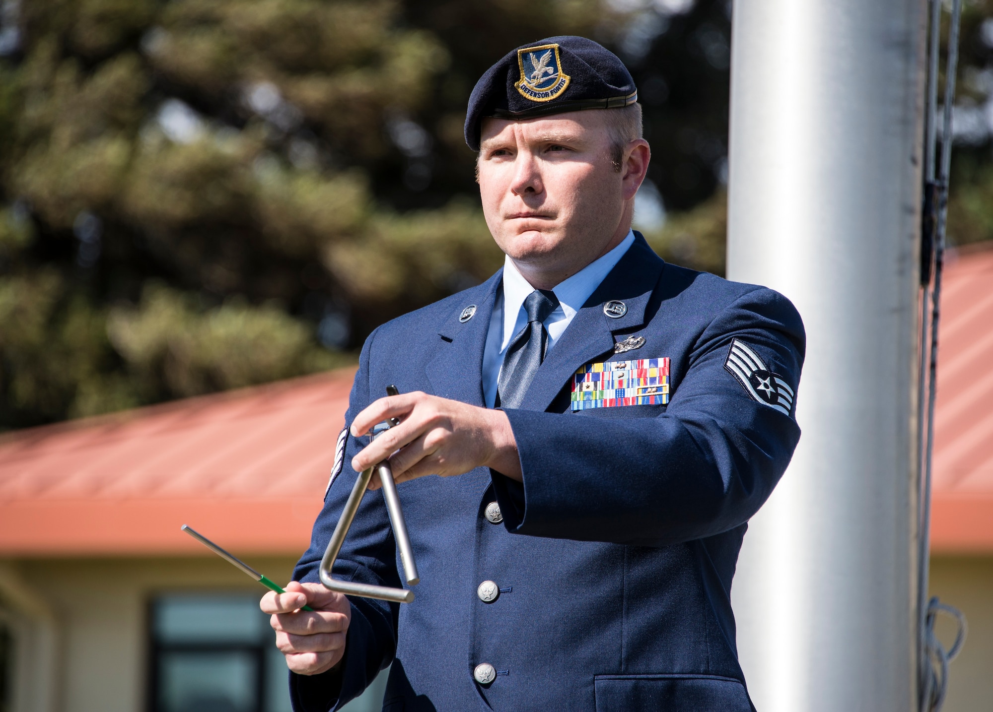 Staff Sgt. Michael Castaneda, 60th Security Forces Squadron, rings a triangle each time the name of a fallen service member is read aloud during a retreat ceremony at Travis Air Force Base, Calif., May 20, 2016. The retreat ceremony concluded a week of activities hosted by base security forces personnel as part of National Police Week. (U.S. Air Force photo by Staff Sgt. Charles Rivezzo)