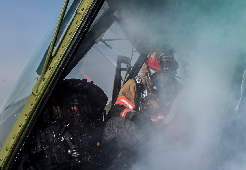 A firefighter from the 5th Civil Engineer Squadron “rescues” an Airman from a smoking aircraft during a simulation at Minot Air Force Base, N.D., May 19, 2016. The Minot AFB fire department train and perform exercises regularly to maintain readiness. (U.S. Air Force photo/Airman 1st Class Christian Sullivan)