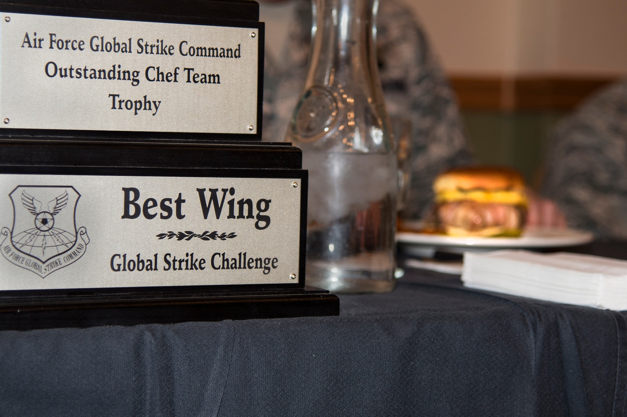 The trophy from the Global Strike Challenge trophy for outstanding chef team sits in front of a panel of judges as they taste test the food made by each team. Three teams consisting of Minot chefs and at least one missile chef competed to go to Barksdale AFB, L.A. for the Global Strike Competition. (U.S. Air Force photo/Airman 1st Class Christian Sullivan)
