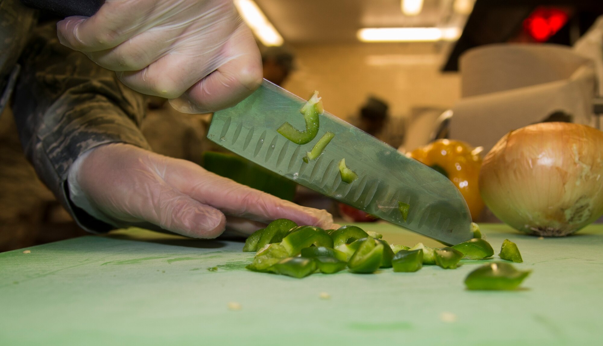 An Airman from the 5th Force Support Squadron cuts peppers during the top chef challenge at Minot Air Force Base, N.D., May 17, 2016. Each team had to make an appetizer, main course and dessert with each containing a secret ingredient in two hours. (U.S. Air Force photo/Airman 1st Class Christian Sullivan)