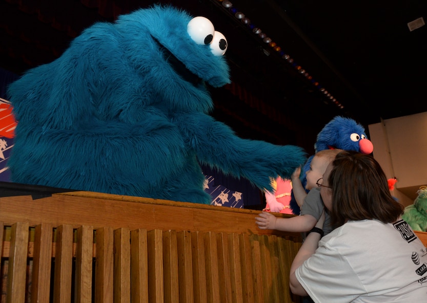 Cookie Monster, a well-known character from Sesame Street, visits with a young child at the base theater at Minot Air Force Base, N.D., May 18, 2016 at the Experience for Military Families tour sponsored by the USO and Sesame Street. In honor of Military Appreciation Month and the 75th anniversary of the USO, this six-month stateside tour kicked off here debuting a new show about transitioning from military life to civilian life. (U.S. Air Force photo/Airman 1st Class Jessica Weissman)
