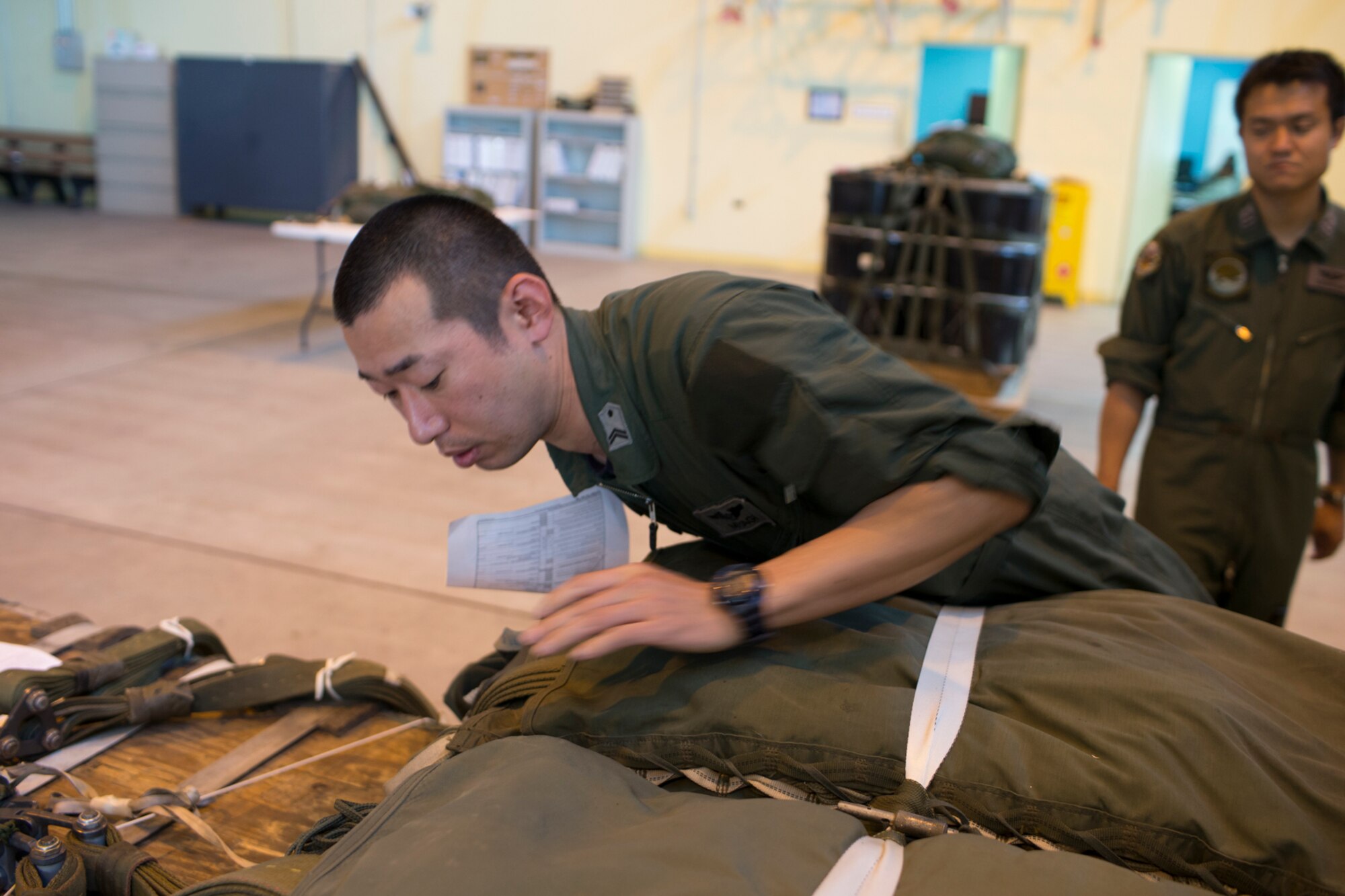 Japan Air Self-Defense Force Tech. Sgt. Shingo Miyagi, 401st Squadron C-130H loadmaster, checks a parachute during the joint airdrop inspection familiarization at Yokota Air Base, Japan, May 18, 2016. Members of JASDF familiarized themselves with JAI procedures in preparation to drop USAF’s heavy equipment and high-velocity container delivery systems during the upcoming exercise Red-Flag Alaska. (U.S. Air Force photo by Yasuo Osakabe/Released)  