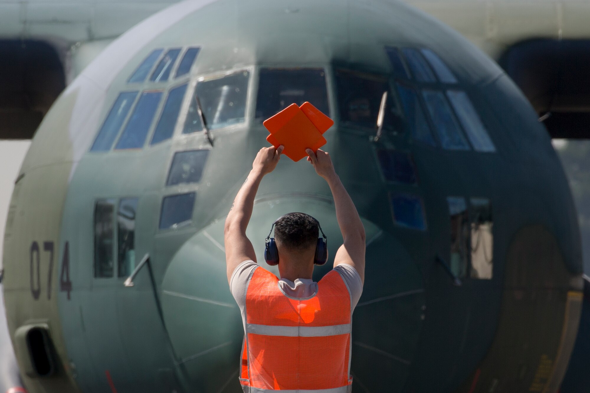 A crew chief with the 374th Aircraft Maintenance Squadron marshals a Japan Air Self-Defense Force’s C-130 Hercules into position on the parking ramp at Yokota Air Base, Japan, May 18, 2016. A JASDF C-130 assigned to the 401st Squadron at Komaki Air Base, Japan. (U.S. Air Force photo by Yasuo Osakabe/Released)