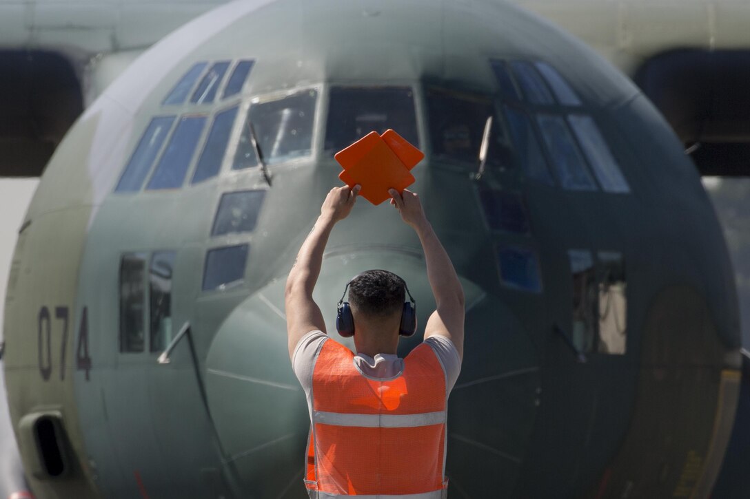 A crew chief with the 374th Aircraft Maintenance Squadron marshals a Japan Air Self-Defense Force’s C-130 Hercules into position on the parking ramp at Yokota Air Base, Japan, May 18, 2016. A JASDF C-130 assigned to the 401st Squadron at Komaki Air Base, Japan. (U.S. Air Force photo by Yasuo Osakabe/Released)