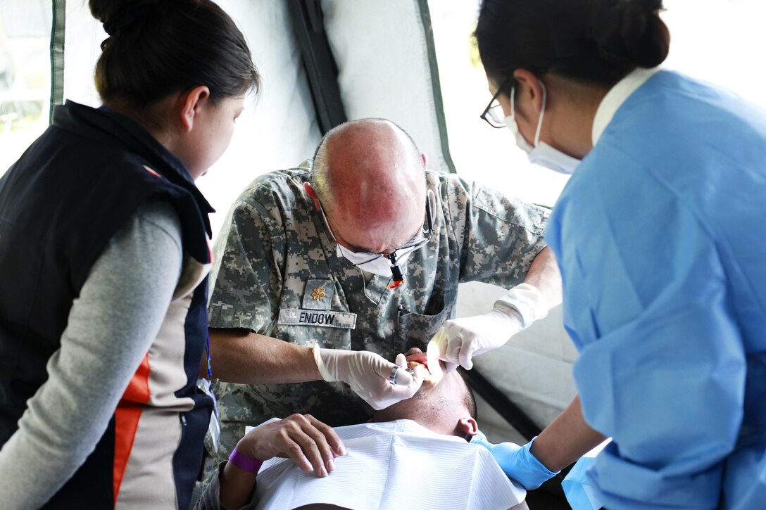 Army Maj. John Endow, center, and Army Pfc. Kontear Peng, right, provide dental care to a patient during Beyond the Horizon 2016 in San Padro, Guatemala, May 16, 2016. Endow is a dentist and Peng is a dental assistant assigned to the 185th Dental Company. Army photo by Spc. Kelson Brooks
