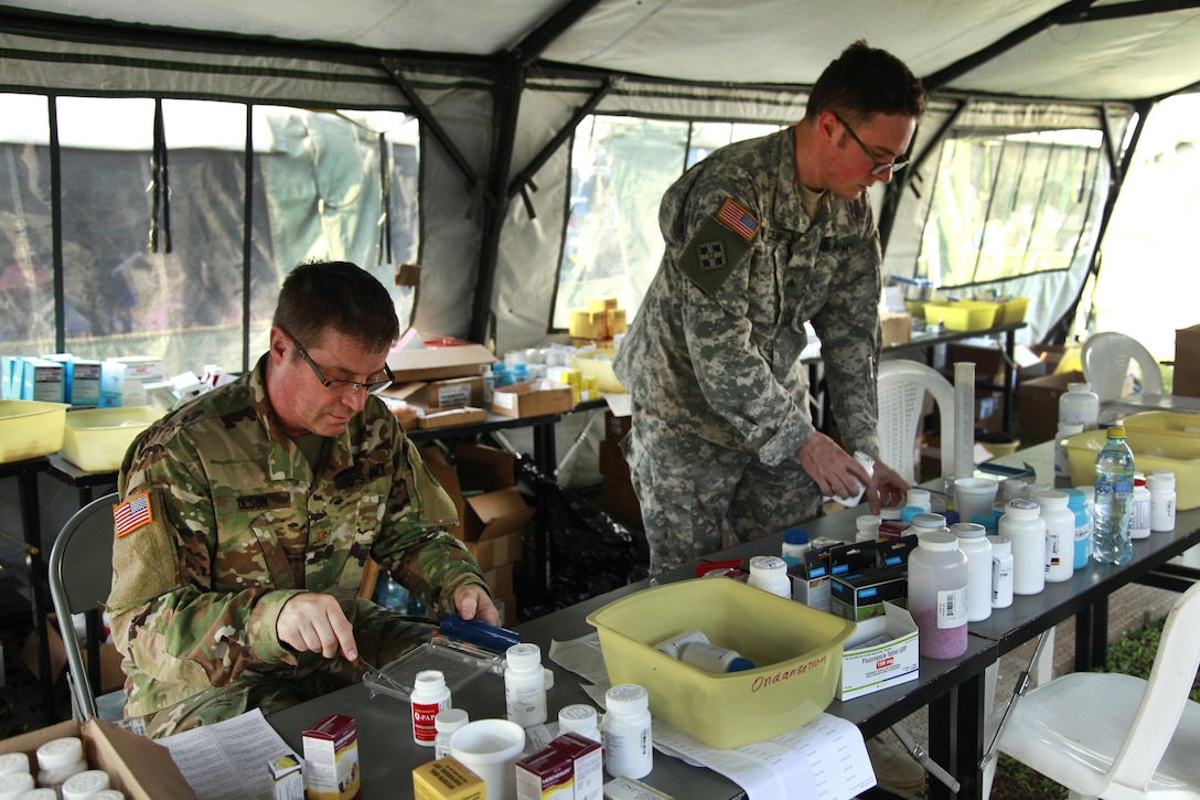 Army Maj. Lance Olsen, left, and Army Sgt. Frisco Cleary sort out medications in the pharmacy tent during Beyond the Horizon 2016 in San Padro, Guatemala, May 16, 2016. Olsen and Cleary are assigned to with the 396th Combat Support Hospital Company. Army photo by Spc. Kelson Brooks 