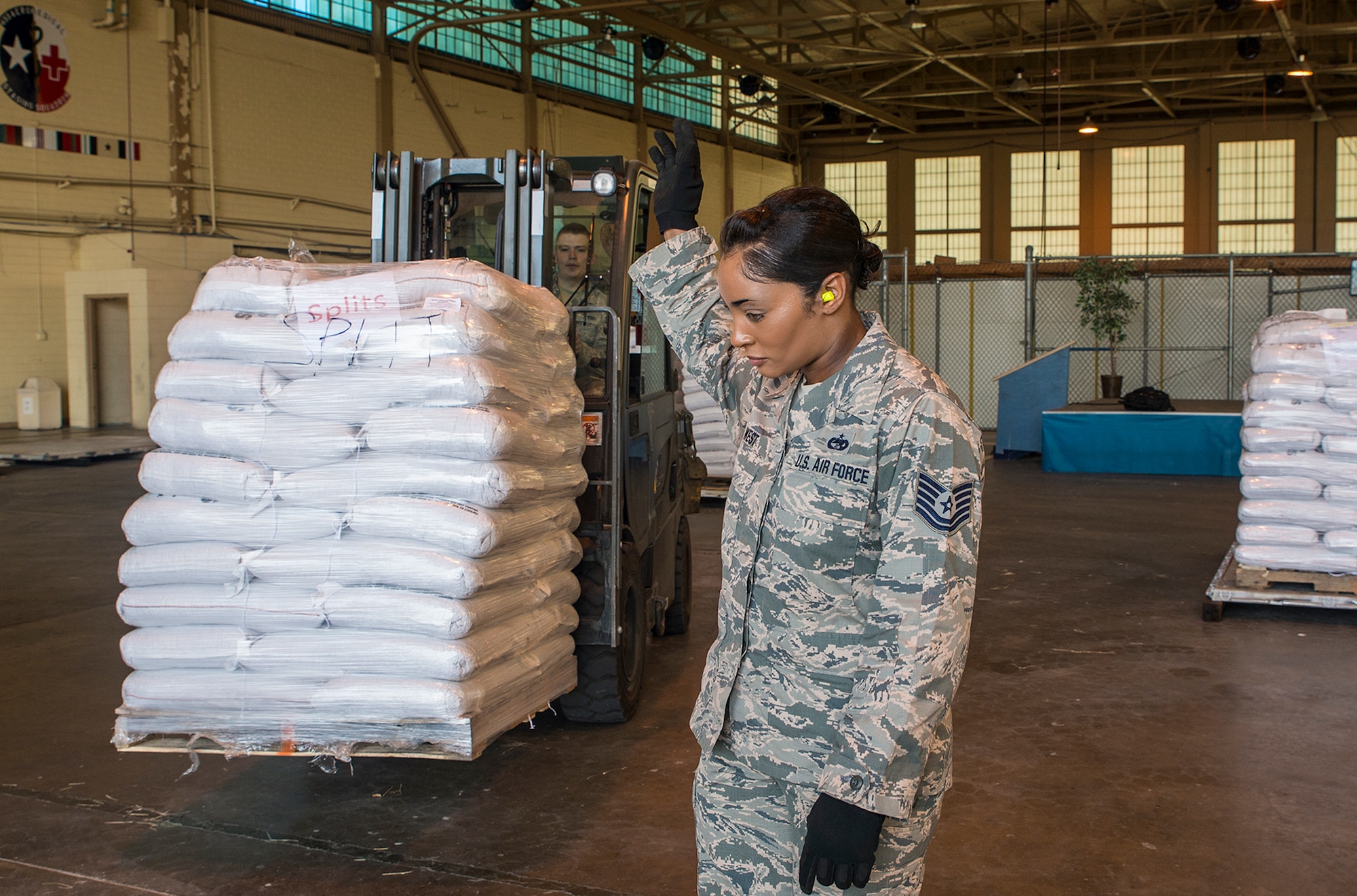 Tech. Sgt. Stephanie West, 502nd Logistics Readiness Squadron information controller, guides a load of rice and beans to an awaiting pallet May 11, 2016 at Joint Base San Antonio-Lackland, Texas. The 433rd Airlift Wing and 502nd Logistics Readiness Squadron worked together to ensure 90,000 pounds of food aid made it to Yoro, Honduras. (U.S. Air Force photo by Benjamin Faske) 