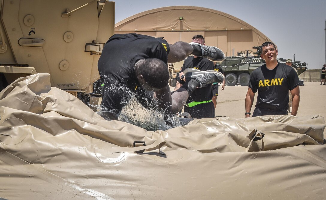 A U.S. Army Reserve soldier with the 369th Chemical Company dives into a blivet, a collapsible water tank, after performing a chemical, biological, radiological and nuclear demonstration in full chemical gear at Camp Arifjan, Kuwait, May 18, 2016. (U.S. Army photo by Sgt. 1st Class Marisol Walker)