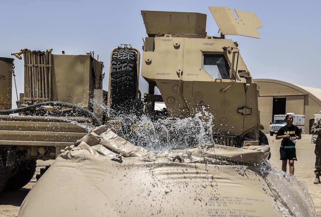 A U.S. Army Reserve soldier with the 369th Chemical Company dives into a blivet, a collapsible water tank, after performing a chemical, biological, radiological and nuclear demonstration in full chemical gear at Camp Arifjan, Kuwait, May 18, 2016. (U.S. Army photo by Sgt. 1st Class Marisol Walker)