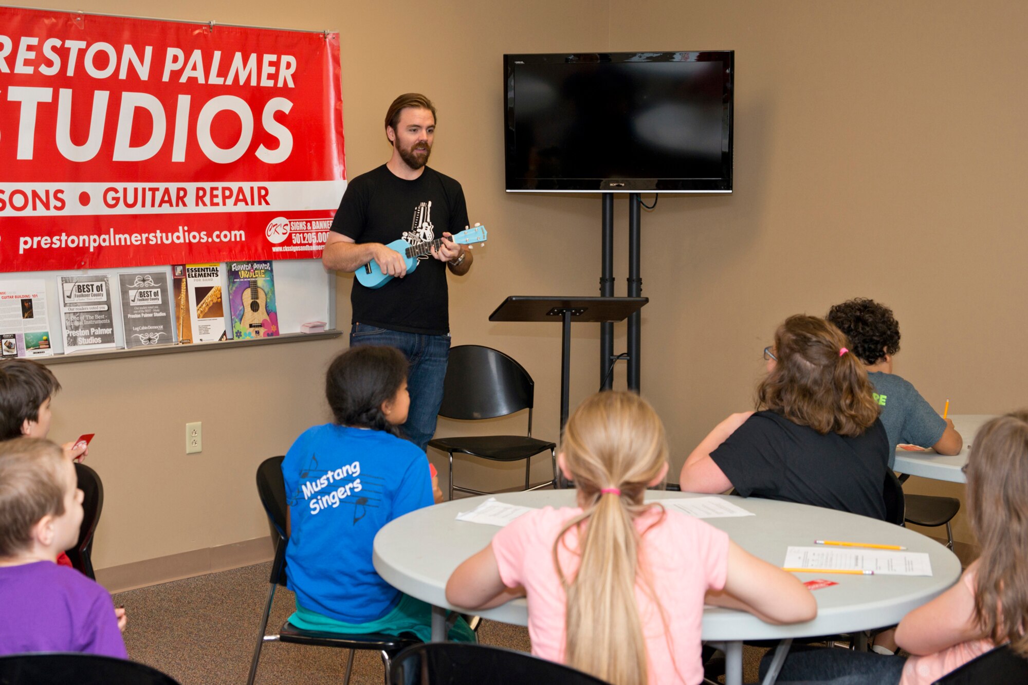Preston Palmer, owner of Preston Palmer Studios, plays a ukulele for a group of Julia Lee Moore Elementary School students during the Fourth Grade Elementary Career Fair held at the Second Baptist Church in Conway Ark., May 17, 2016.  The event exposed more than 250 students to careers they might not have considered and the level of education those careers may require. (U.S. Air Force photo by Master Sgt. Jeff Walston/Released)  