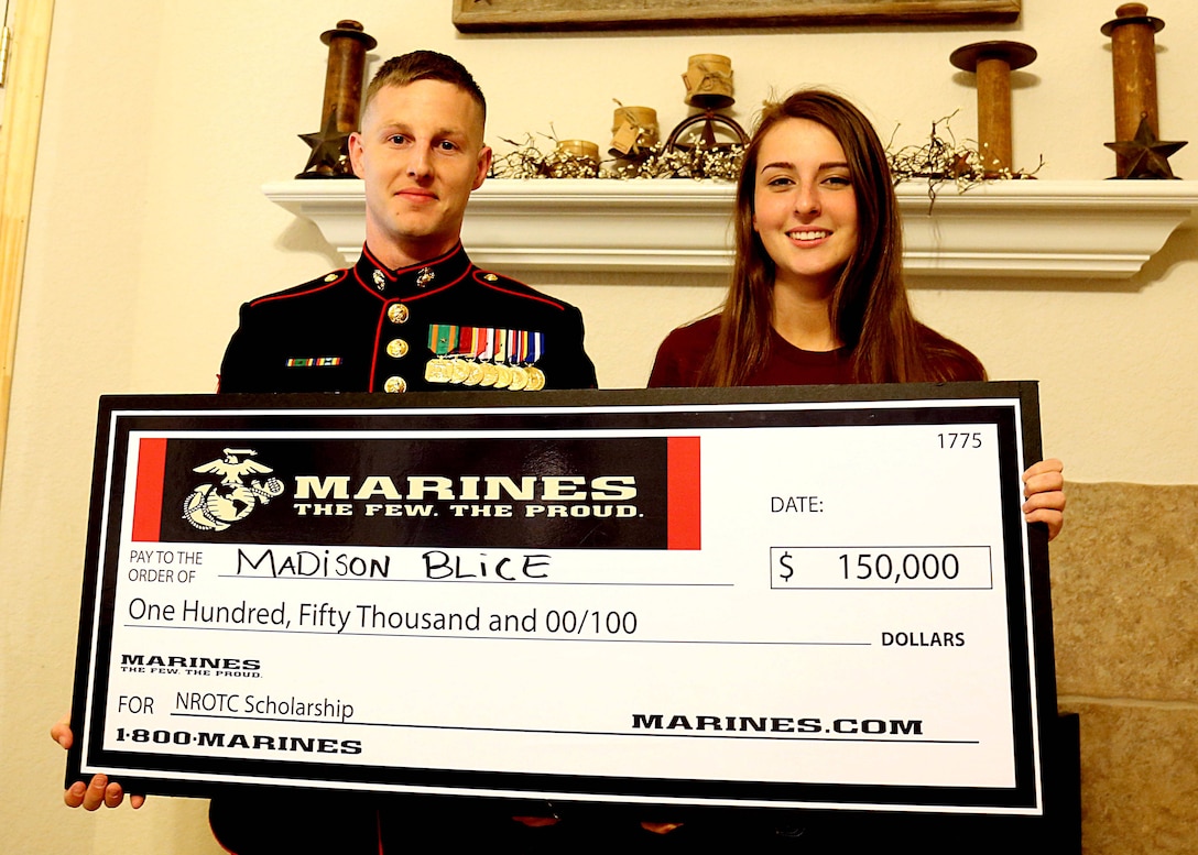 Staff Sgt. Joshua Wazdrag presents Madison Blice with a Naval Reserve Officer Training Corps Scholarship check during a surprise presentation for her and her family at their home in Montgomery, Tx., April 7, 2016. Wazdrag is a recruiter with Recruiting Substation Conroe, Marine Corps Recruiting Station Houston. Blice is an 18-year-old senior with Montgomery High School and a Montgomery, Tx. native. 