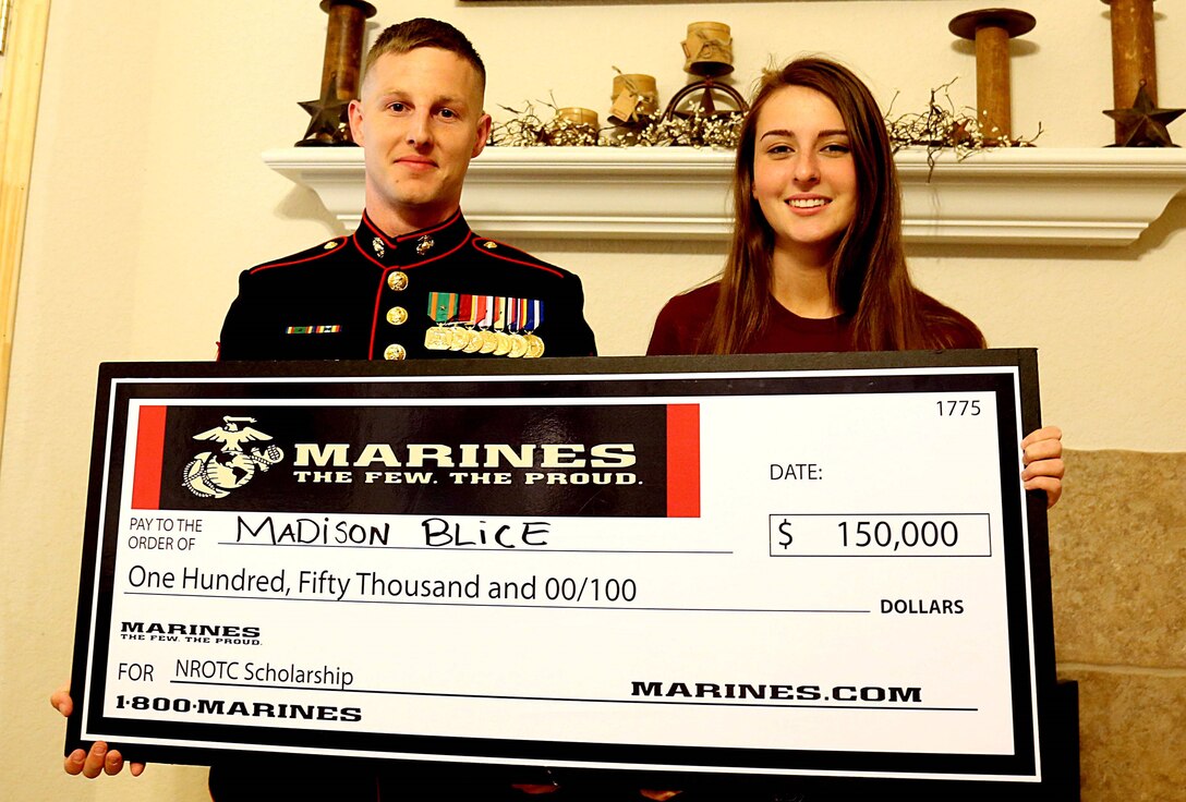 Staff Sgt. Joshua Wazdrag presents Madison Blice with a Naval Reserve Officer Training Corps Scholarship check during a surprise presentation for her and her family at their home in Montgomery, Tx., April 7, 2016. Wazdrag is a recruiter with Recruiting Substation Conroe, Marine Corps Recruiting Station Houston. Blice is an 18-year-old senior with Montgomery High School and a Montgomery, Tx. native. 