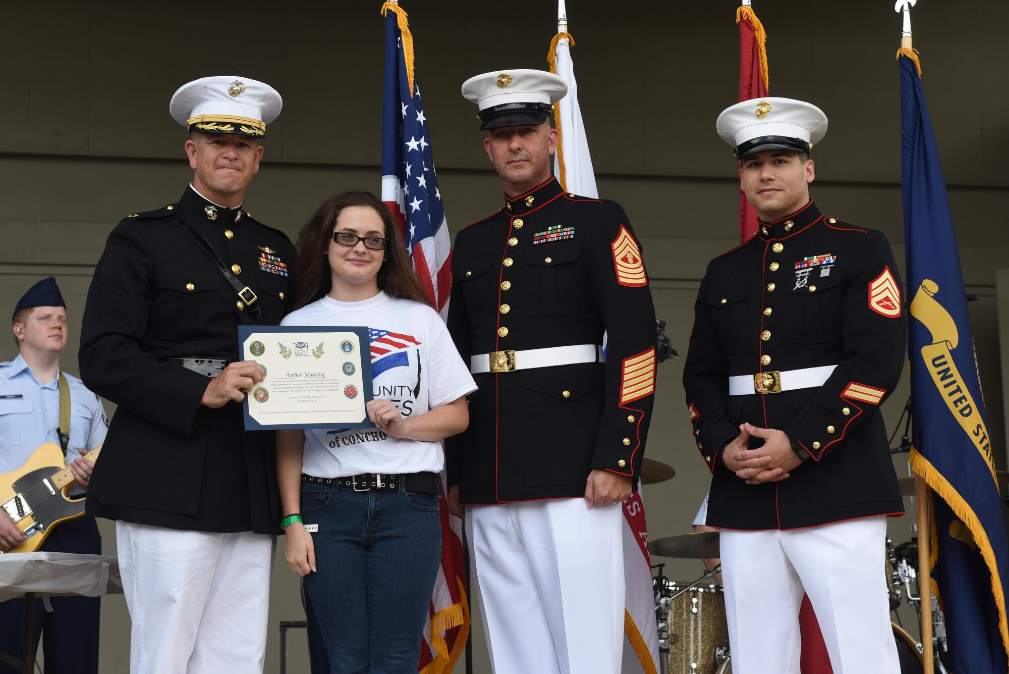 U.S. Marine Corps Maj. Andrew Armstrong, Marine Corps Detachment Commanding Officer, presents a certificate to Amber Mooring, high school student, for choosing to enlist in the Marine Corps, at the RiverStage in San Angelo, Texas, May 21, 2016. (U.S. Air Force photo by Airman 1st Class Chase Sousa/Released)