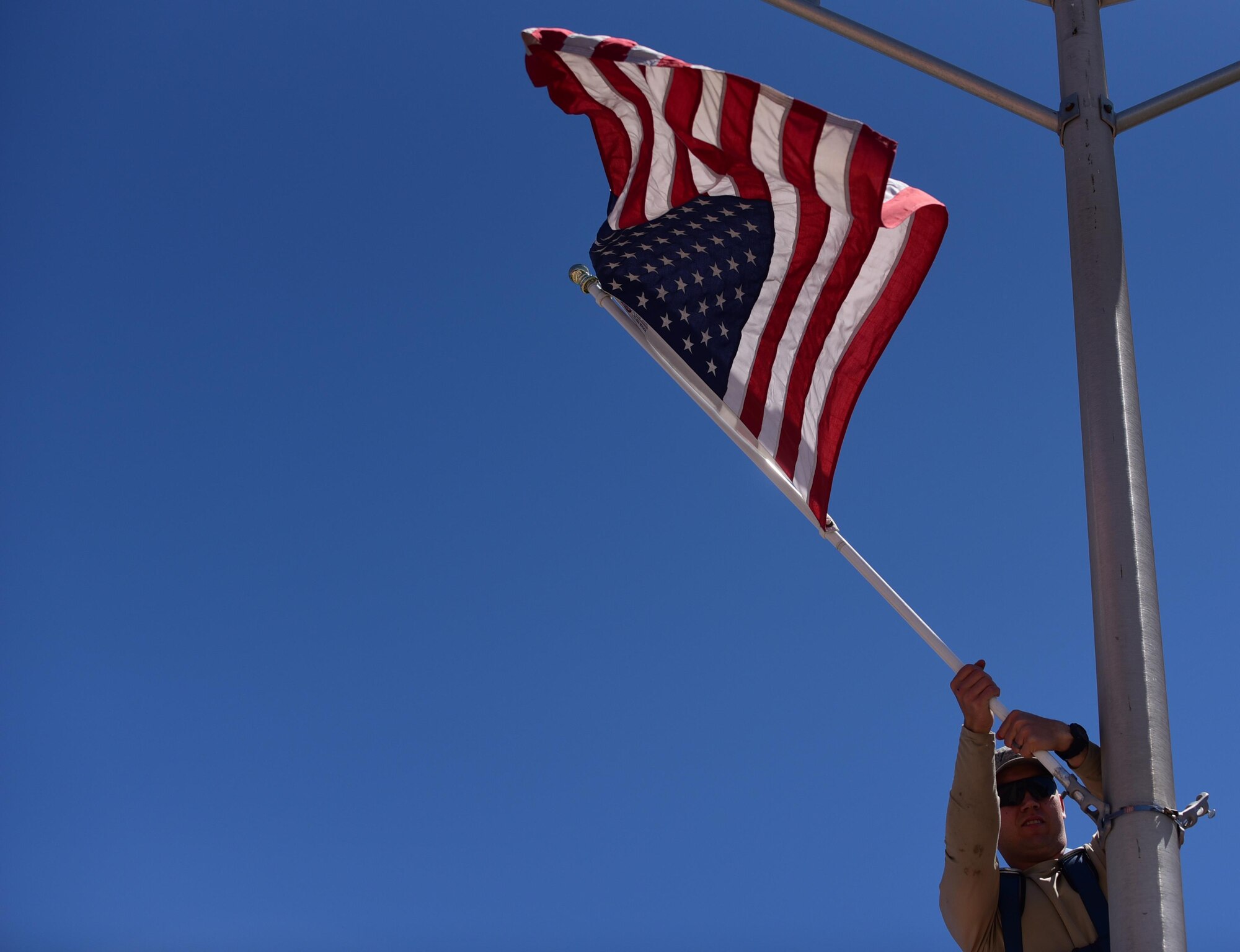 Staff Sgt. Steven Price, 21st Civil Engineer Squadron structural journeyman, hangs American flags for Memorial Day at Peterson Air Force Base, Colo., May 23, 2016.  CE is responsible for placing around 130 flags out along the main roads of the base at this time every year. (U.S. Air Force photo by Staff Sgt. Amber Grimm)