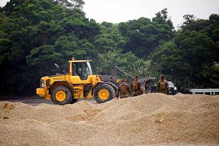 U.S. Marine Corps Marines observe Airmen operating heavy equipment during a two day joint airfield damage repair exercise May 18, 2016 at Kadena Air Base, Japan. Airmen demonstrated the method and technique the U.S. Air Force uses for airfield damage repair the first day of the exercise and the Marines applied those techniques during the second day. 