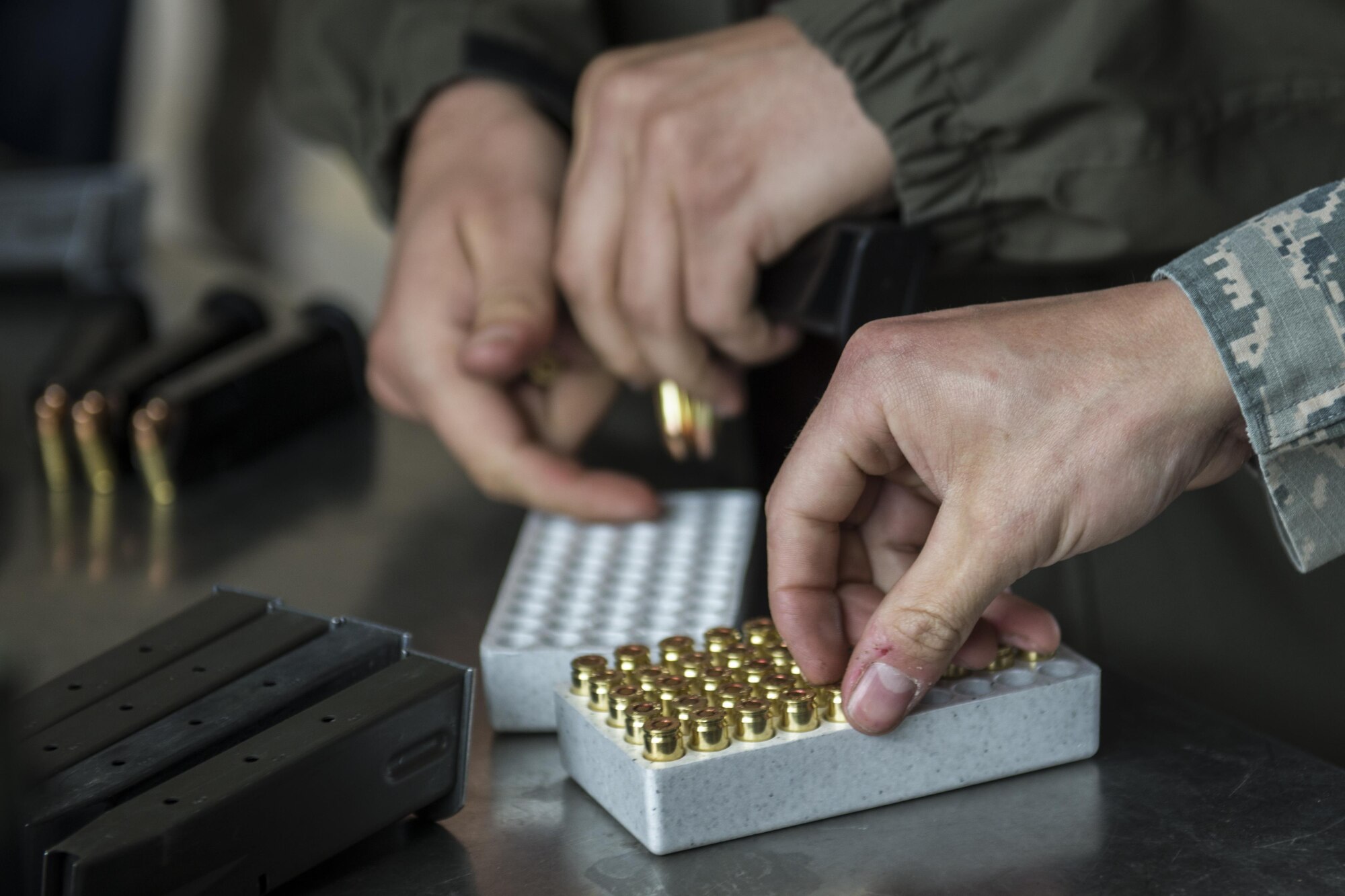 U.S. Air Force office of Special Investigations Special Agent Sam Lee, with Detachment 632, and Airman 1st Class Digiacinto, a 354th Security Forces Squadron response force member, prepare magazines for a small arms competition at Eielson Air Force Base, Alaska, May 17, 2016, as part of National Police Week activities. The small arms competition was one of the main events for the week, along with equipment displays, a military working dog competition and the Fallen Heroes 5K Run/Ruck. (U.S. Air Force photo by Staff Sgt. Joshua Turner/Released)