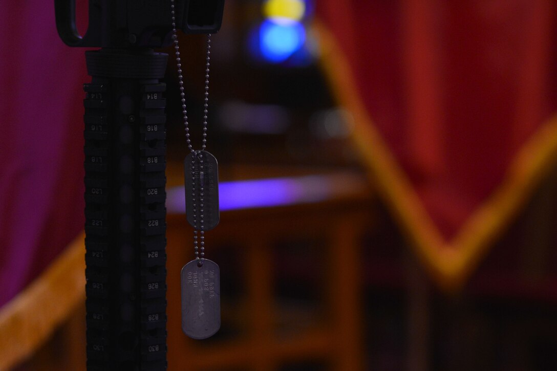 Dog tags hang from a battlefield cross displayed during the U.S. Army Transportation Corps Wreath Laying Ceremony at Fort Eustis, Va., May 24, 2016.  The cross pays homage to Service members who lost their lives, and is composed of combat boots, a rifle, helmet and dog tags. (U.S. Air Force photo by Staff Sgt. Natasha Stannard)