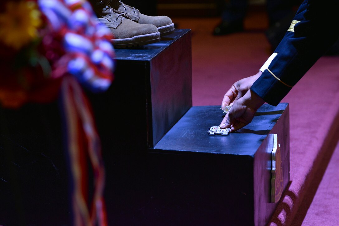 U.S. Army Transportation Corps leaders place coins on the battlefield cross during a Wreath Laying Ceremony at Fort Eustis, Va., May 24, 2016.  The coins are placed as a way to honor the sacrifices fallen U.S. Service members made for the nation. (U.S. Air Force photo by Staff Sgt. Natasha Stannard)