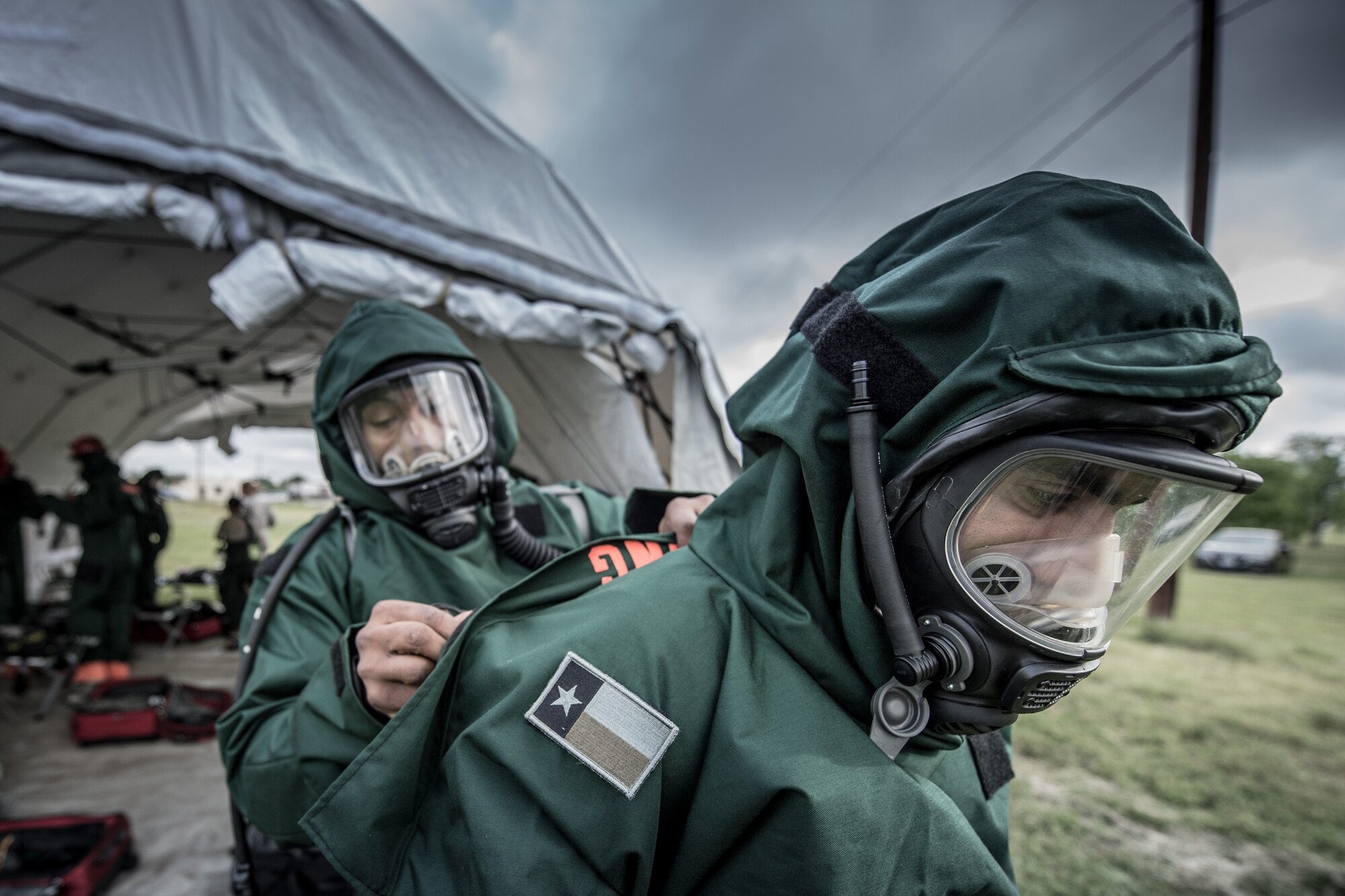1st Lt. Lenton Johnson helps Tech. Sgt. Edwin Bello secure his chemical protective suit at Joint Base San Antonio, Texas, April 10, 2016. These airmen are members of the 149th Force Support Squadron, Fatality Search and Recovery Team. Members of the FSRT are training on how to move into a contaminated area and recover remains after a chemical disaster. (U.S. Air National Guard photo by Tech. Sgt. Eric L. Wilson)
