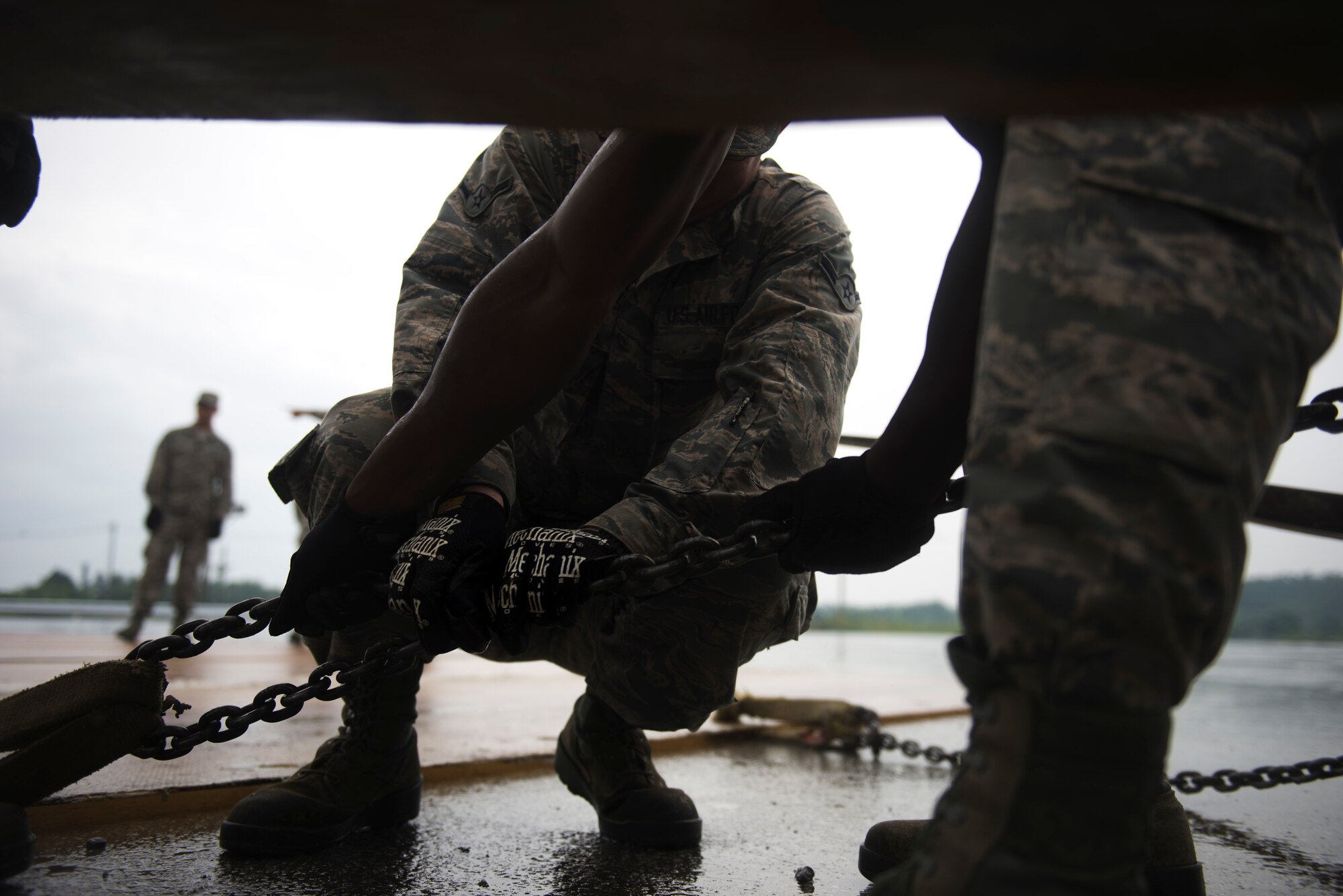 Airmen attach the chains from a fiberglass mat to the bottom rail of a forklift during an airfield damage repair exercise May 18, 2016 on Kadena Air Base, Japan. During the exercise the fiberglass mat team had to maneuver and unfold mats to fit over simulated filled craters. (U.S. Air Force photo by Senior Airman Omari Bernard)