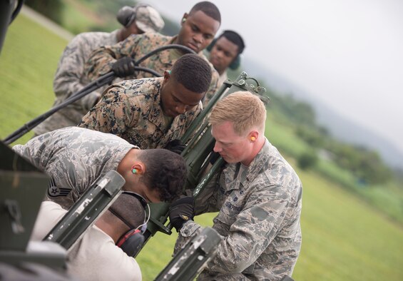 U.S. Airmen and Marines work together to plant stakes into the ground to create a mobile aircraft arresting system t Kadena Air Base, Japan, May 19, 2016.  Marines from the Marine Wing Support Squadron 172 worked alongside 18th Civil Engineer Squadron Airmen in a joint airfield damage and repair contingency exercise to improve their response capabilities. (U.S. Air Force photo by Senior Airman Omari Bernard/Released)